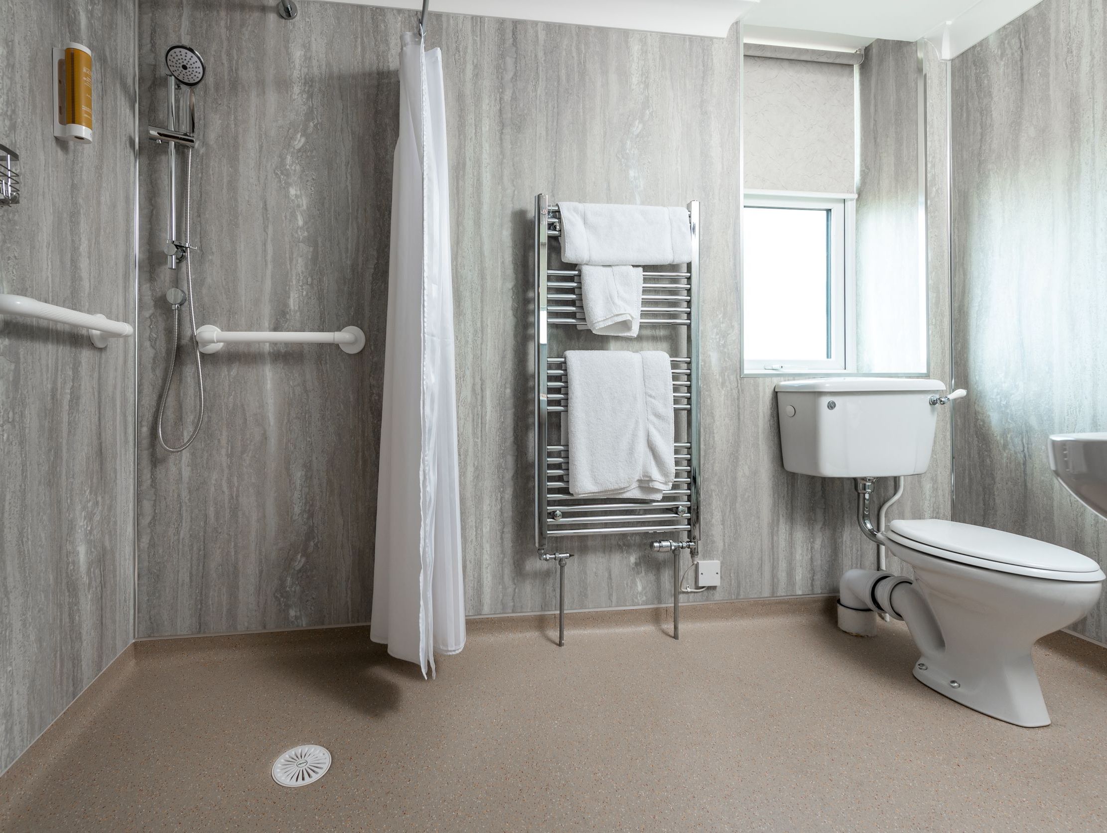 Accessible bathroom with walk-in shower, grab bars, and a toilet.