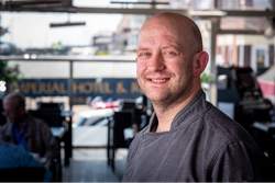 Smiling chef standing inside Imperial Hotel restaurant