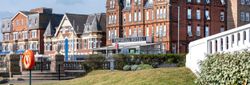 Exterior view of the Imperial Hotel with red brick architecture beside a pond and grassy area