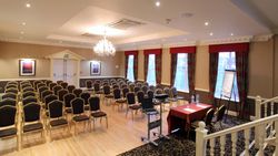 Conference room set up with rows of chairs, a presentation table, and a flip chart