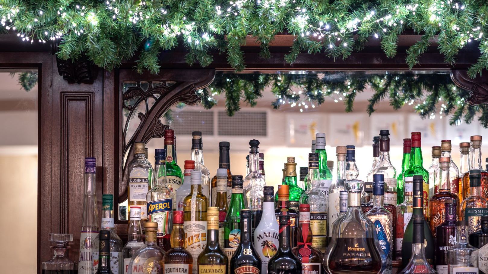 Bar shelf with various bottles of liquor and festive garland decoration