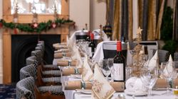 Elegant dinner table setup at a hotel with festive decorations, wine bottles, crackers, and folded napkins.