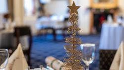 Festive table setting with a gold wire Christmas tree centerpiece topped with a star.