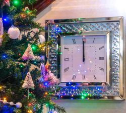 Decorated Christmas tree next to a wall clock striking midnight