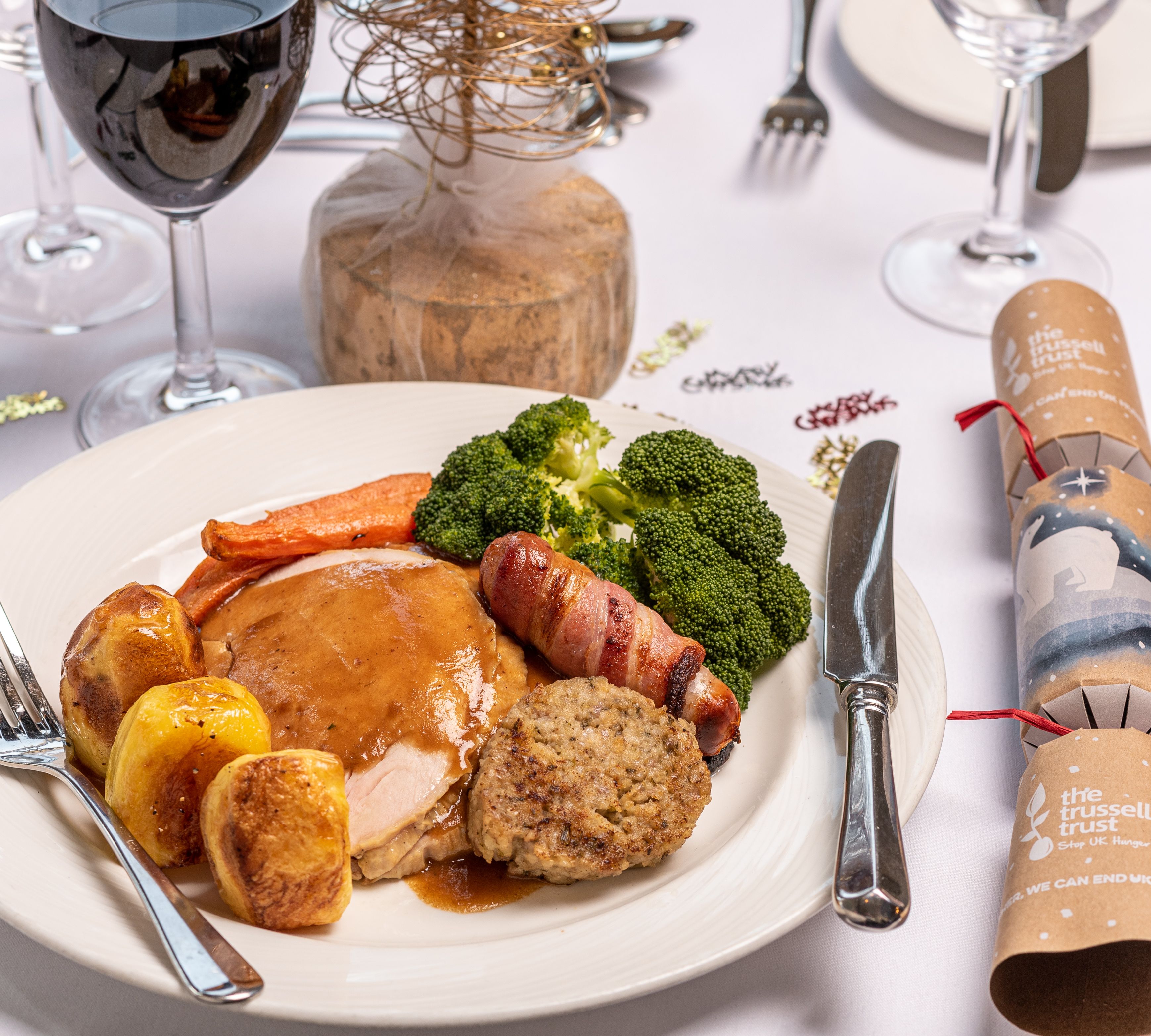 A traditional Christmas roast dinner with turkey, roast potatoes, vegetables, and stuffing, served with gravy on a white plate.