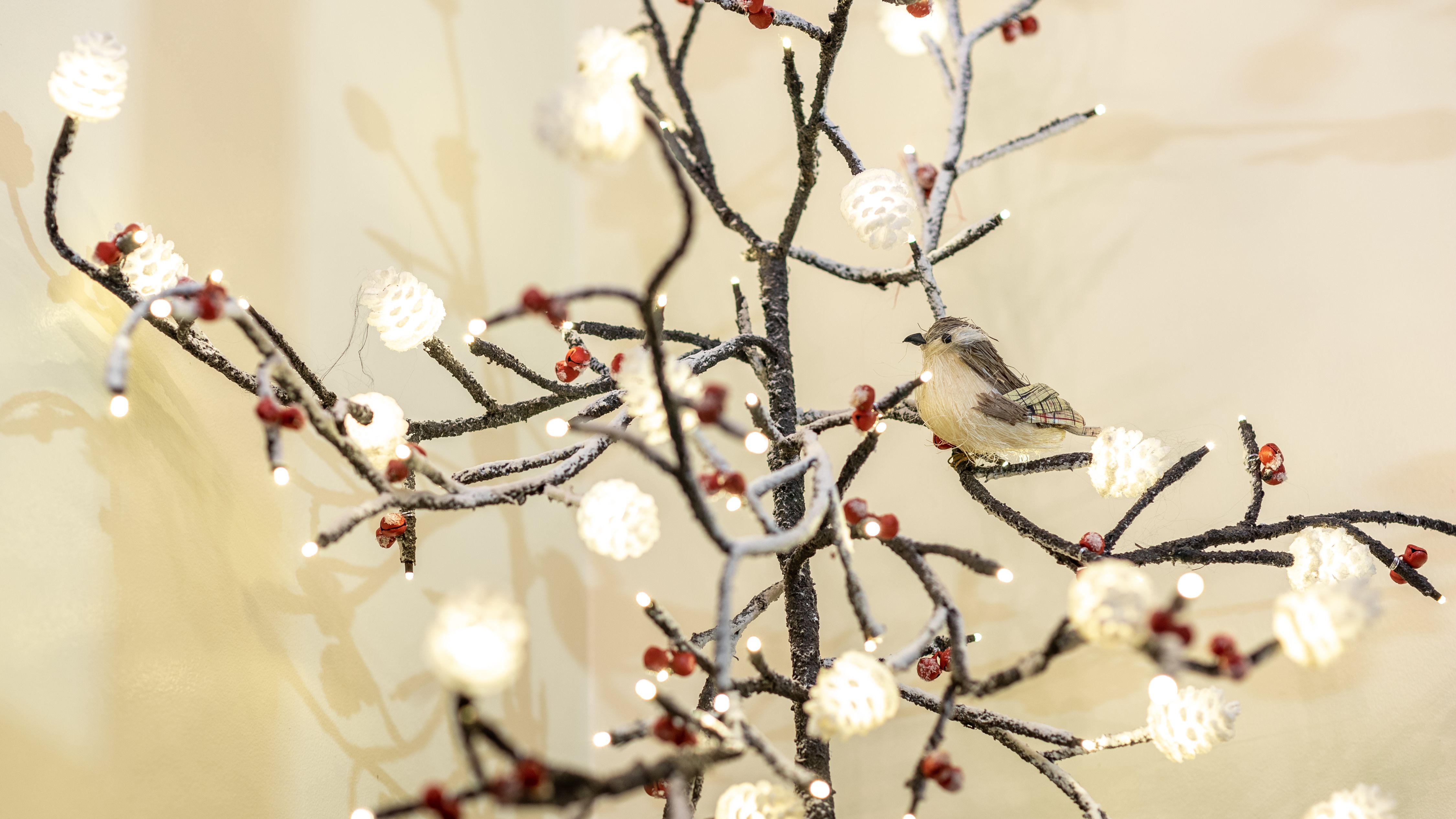 Decorative bird perched on a festive branch with lights and faux berries