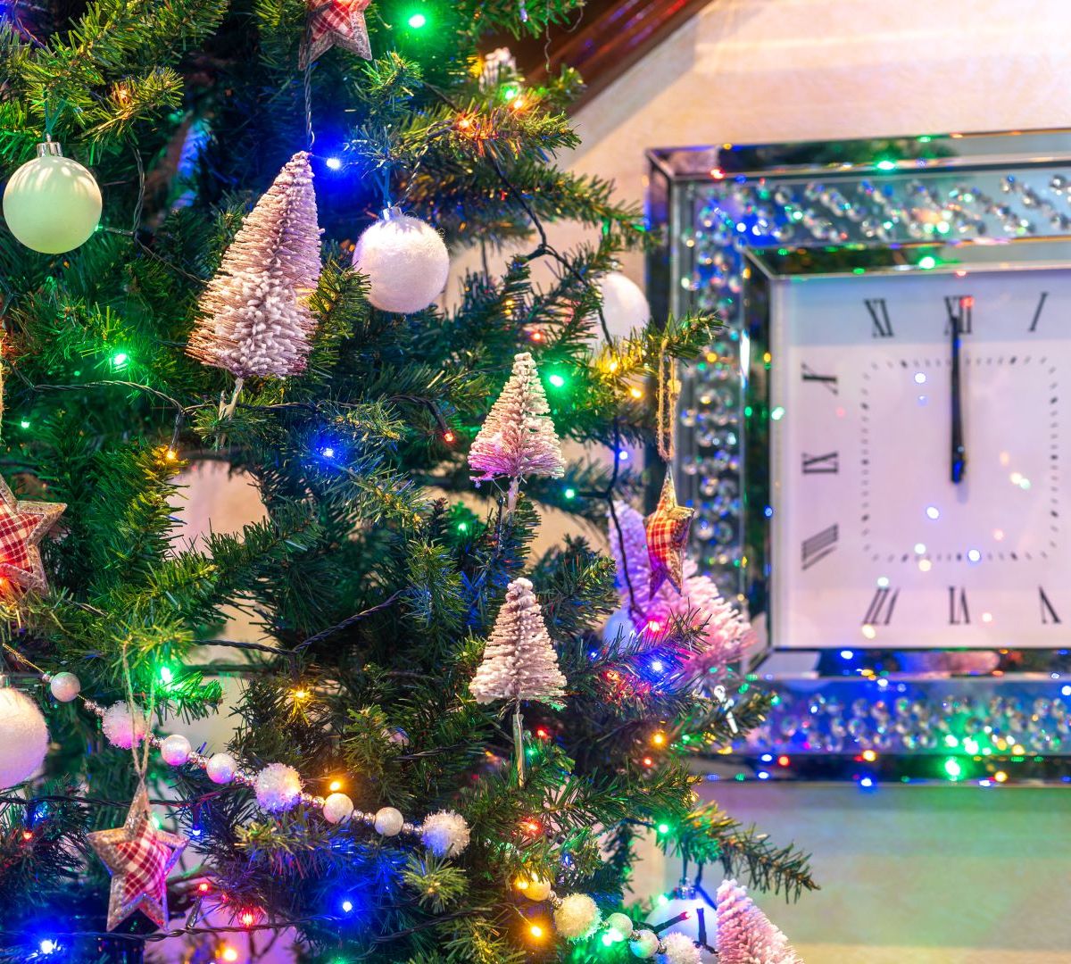 Decorated Christmas tree with ornaments and a clock showing midnight.