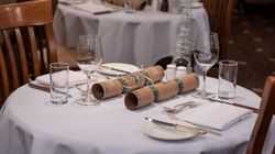 Elegant restaurant table setting with glasses, silverware, napkins, plates, and Christmas crackers