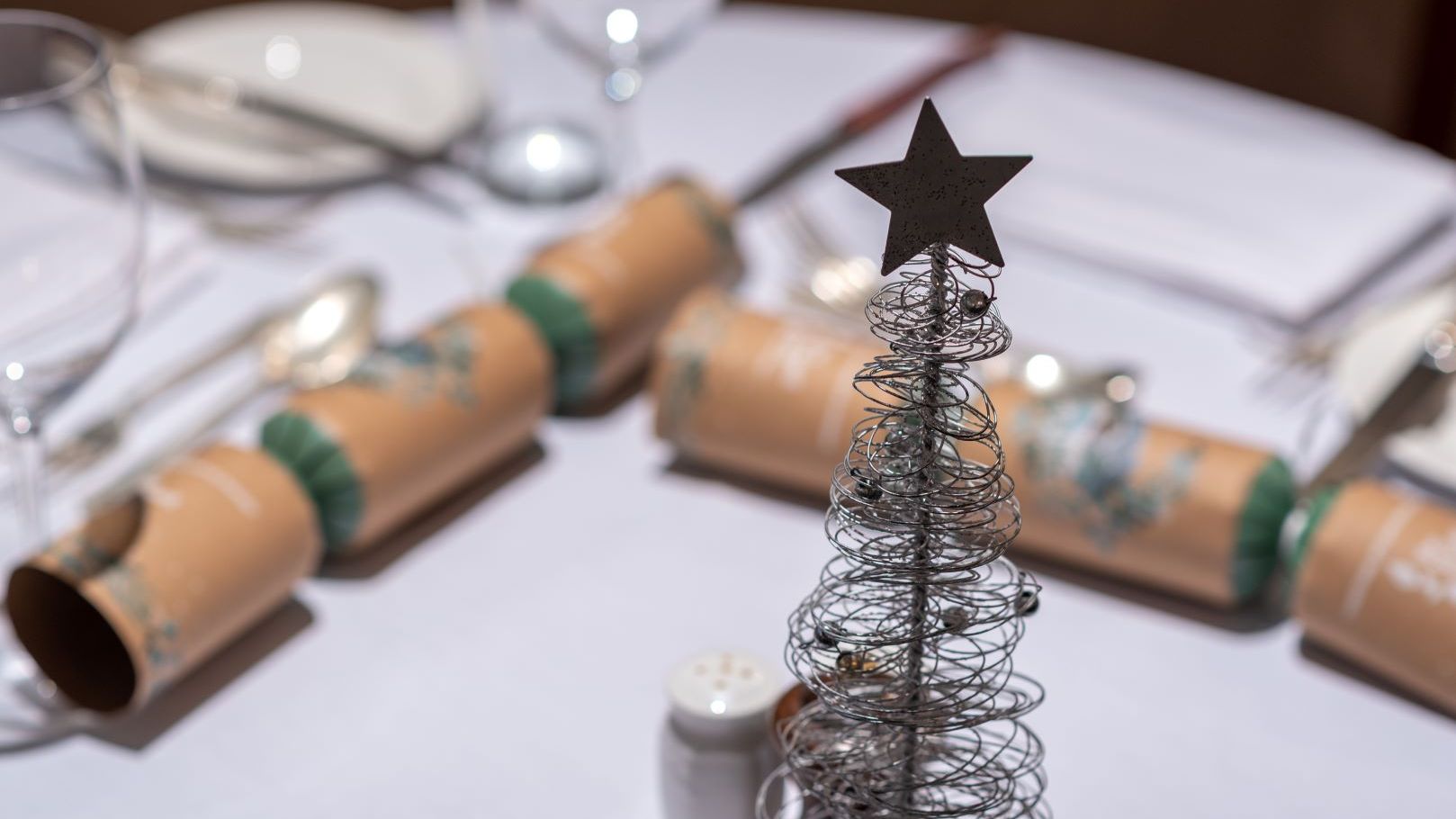 Festive table setting with wire Christmas tree centerpiece and crackers
