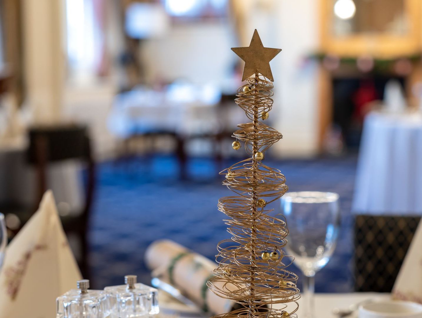 Wire Christmas tree centerpiece with gold star on dining table