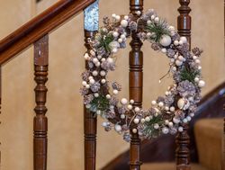 Festive wreath with pinecones and white berries hanging on a staircase railing