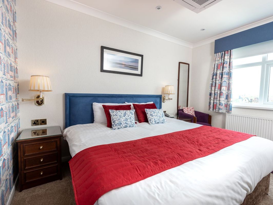 Double bedroom with bright decor, red accents, and large window
