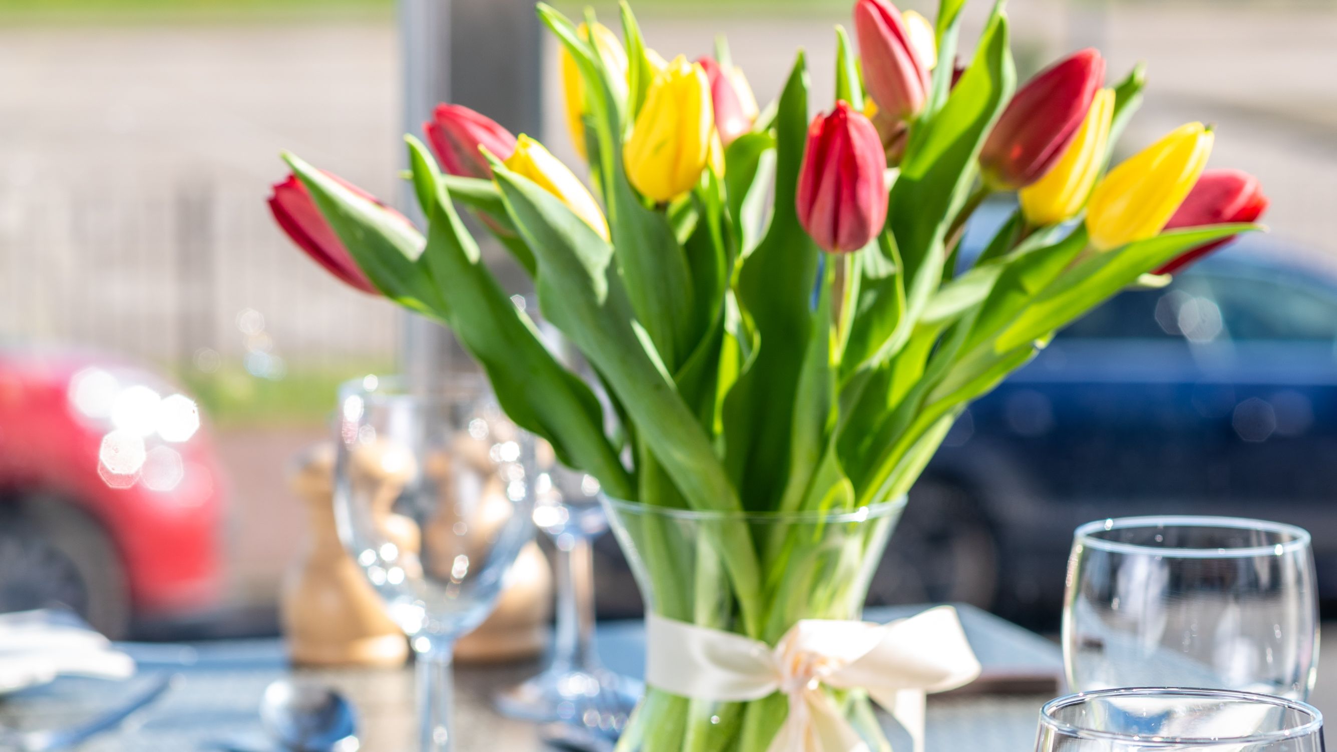 A dining table set with glassware, cutlery, a vase of red and yellow tulips, and a menu titled 'The Terrace'.