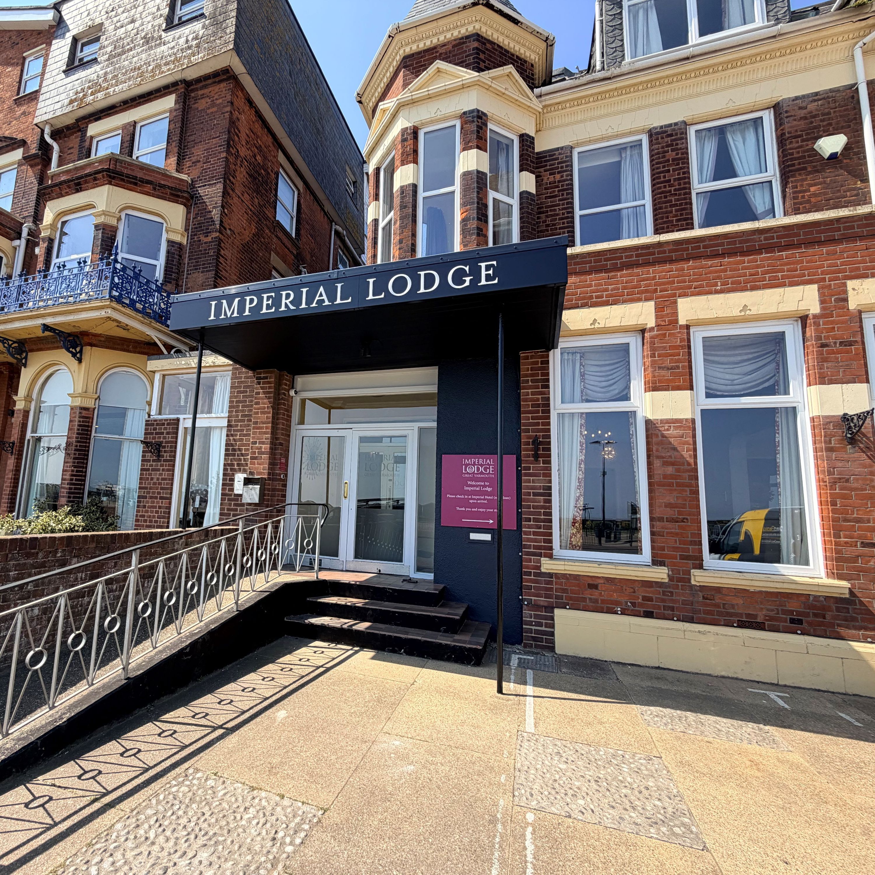 Entrance to Imperial Lodge on North Drive, Great Yarmouth, with black canopy sign and red-brick façade