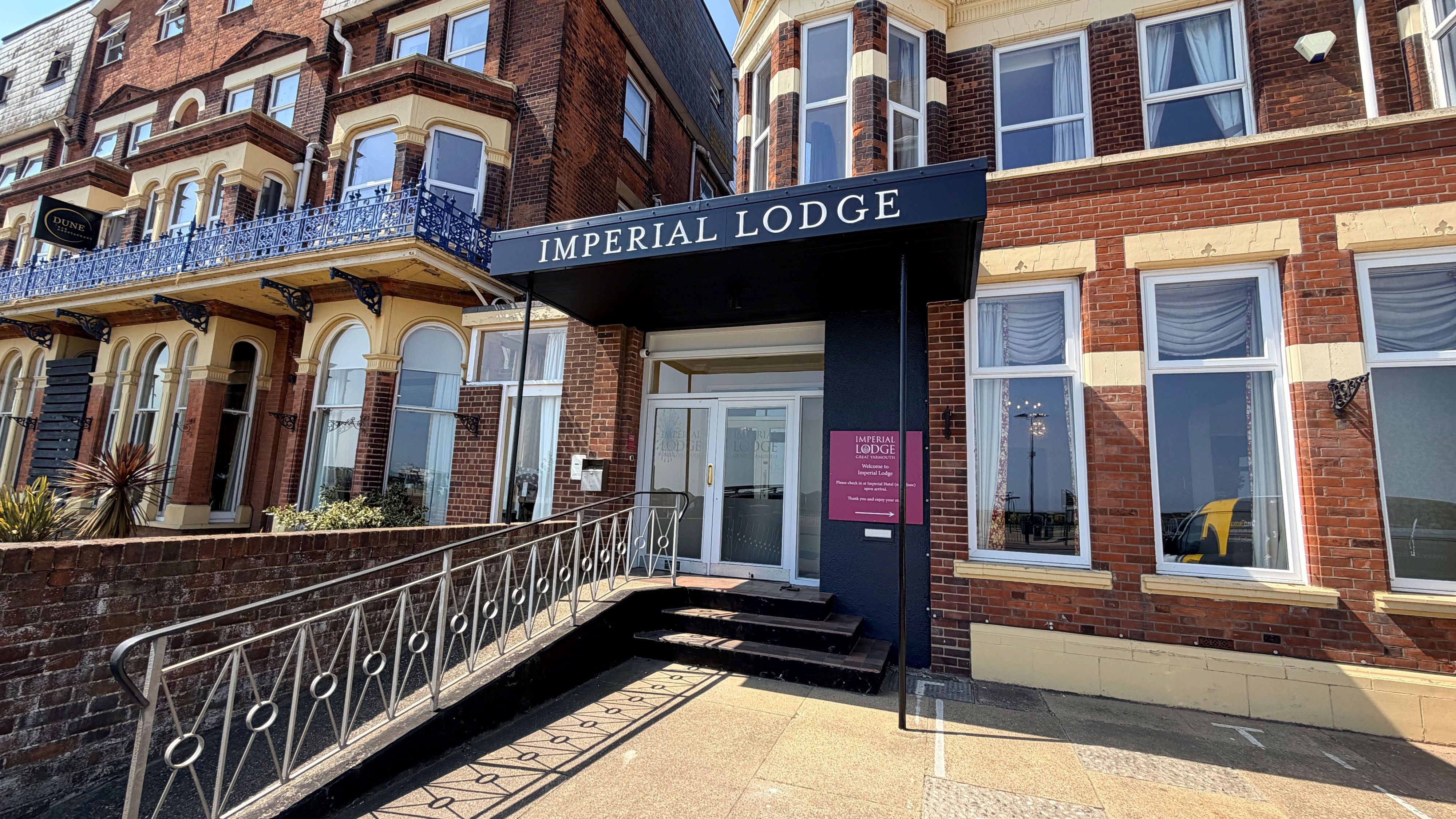 Entrance to Imperial Lodge on North Drive, Great Yarmouth, with black canopy sign and red-brick façade