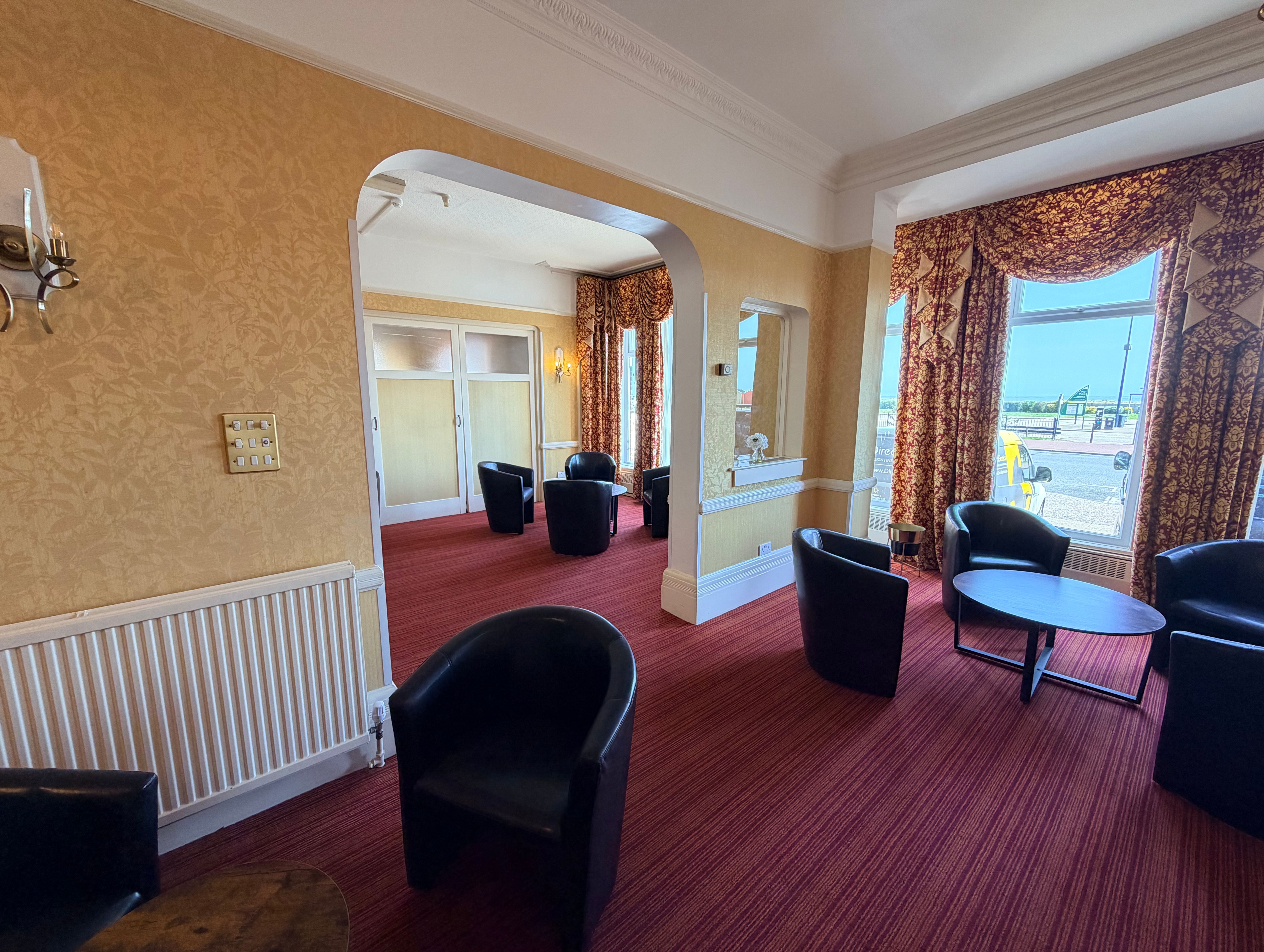 Lounge area with black armchairs, round tables and patterned curtains in a traditional interior
