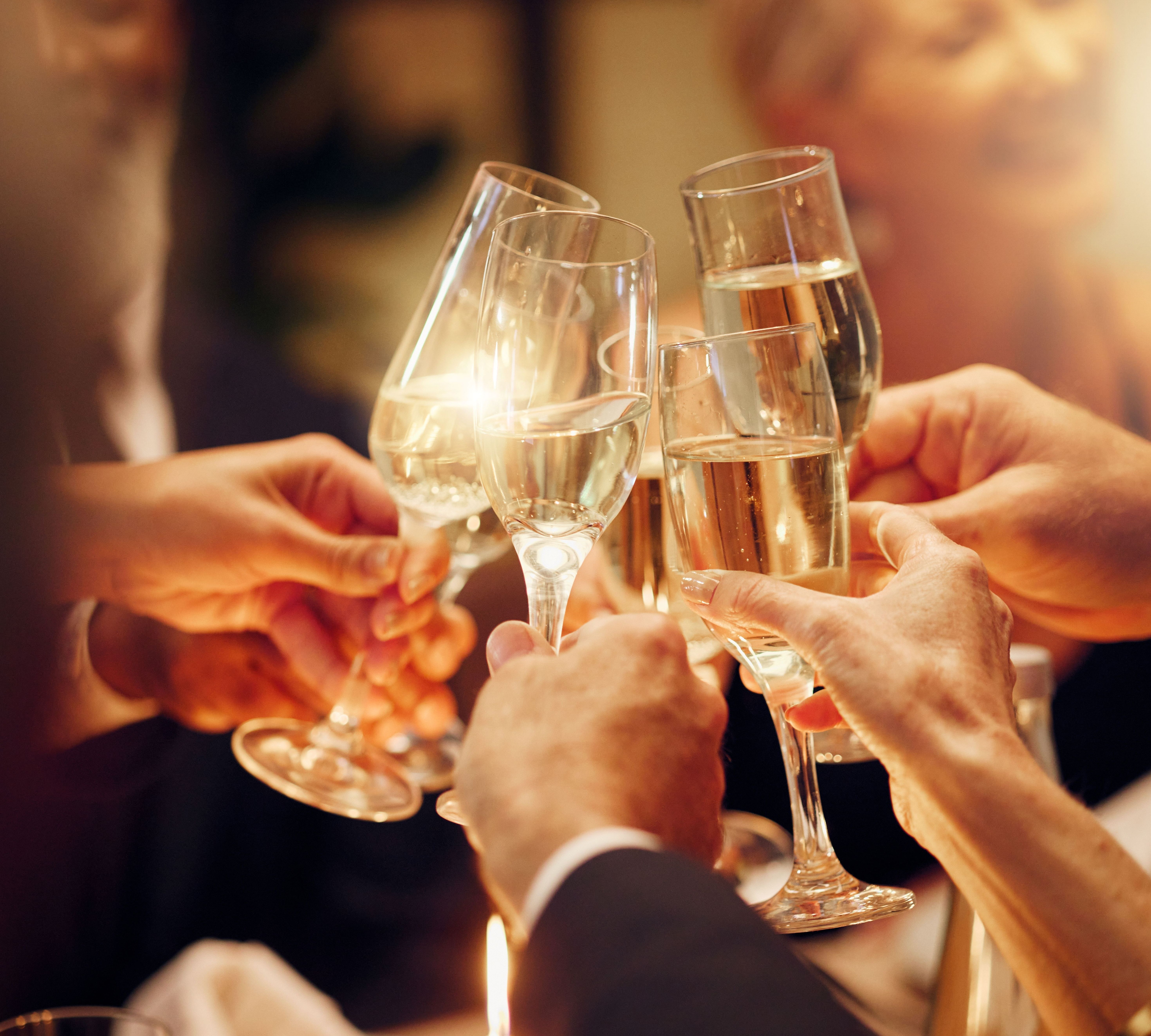 Close-up of people clinking champagne flutes in a toast at an evening celebration