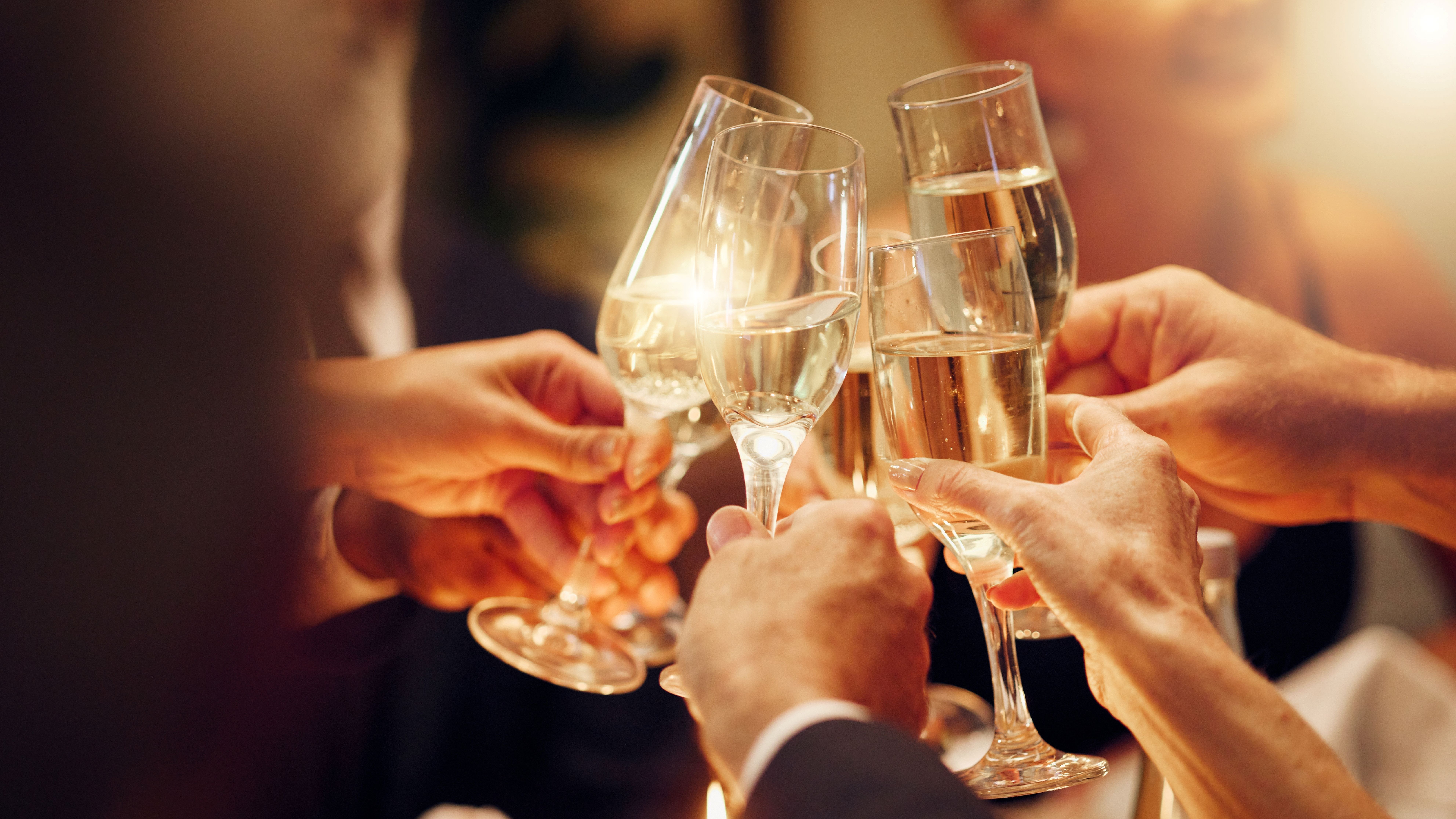 Close-up of people clinking champagne flutes in a toast at an evening celebration