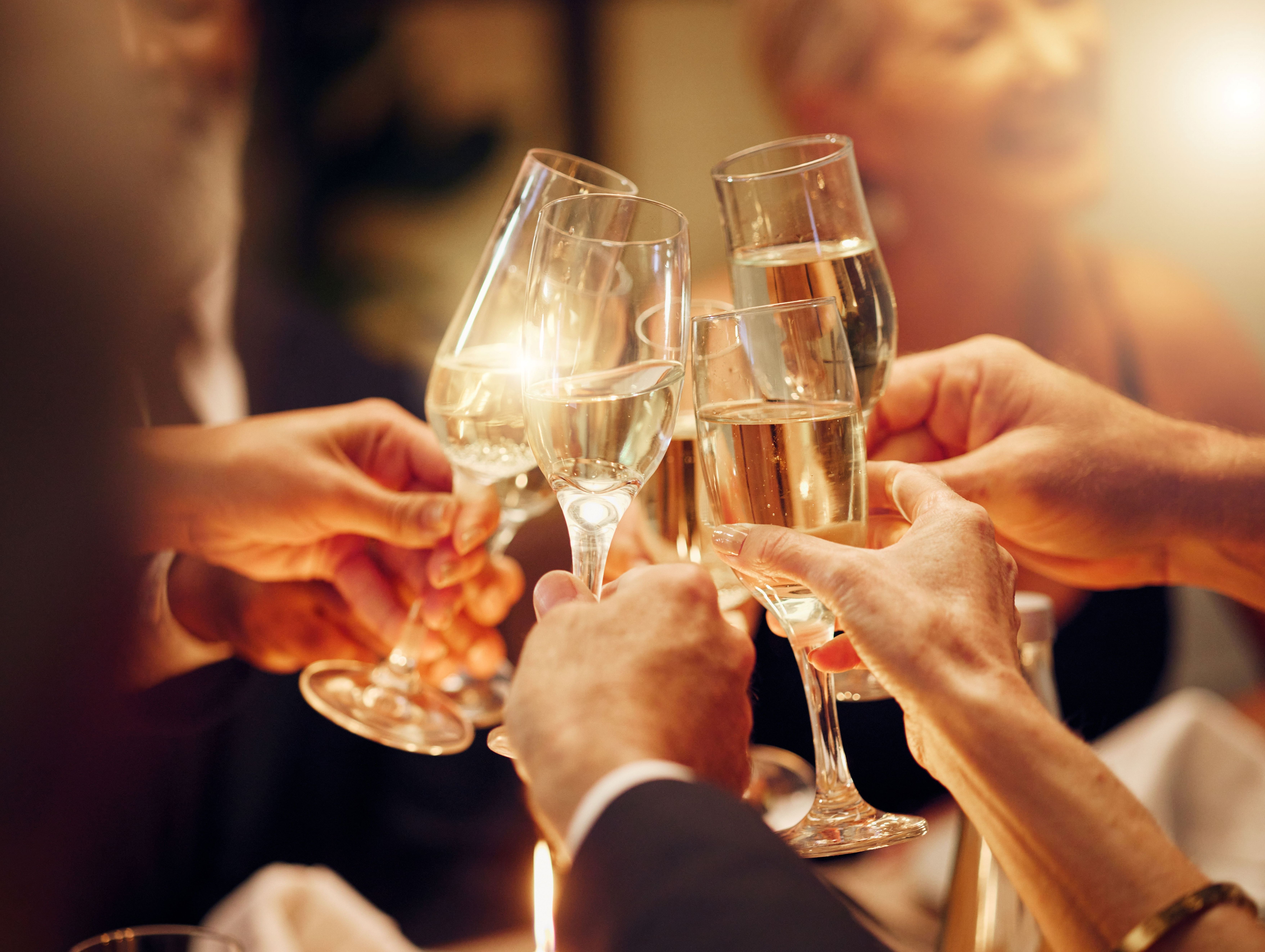 Close-up of people clinking champagne flutes in a toast at an evening celebration