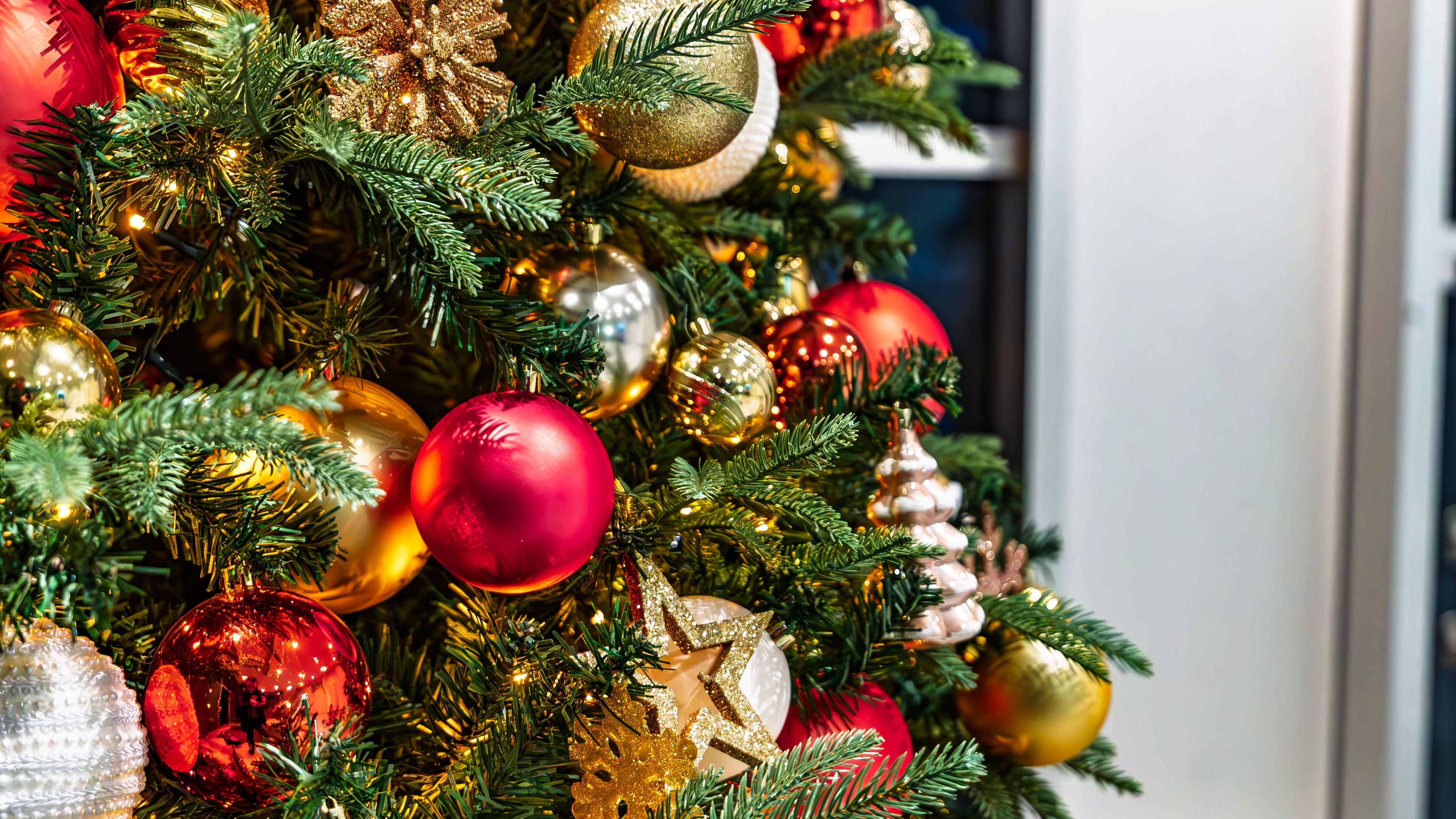 Close-up of a decorated Christmas tree with red and gold baubles, glittery snowflakes and warm fairy lights
