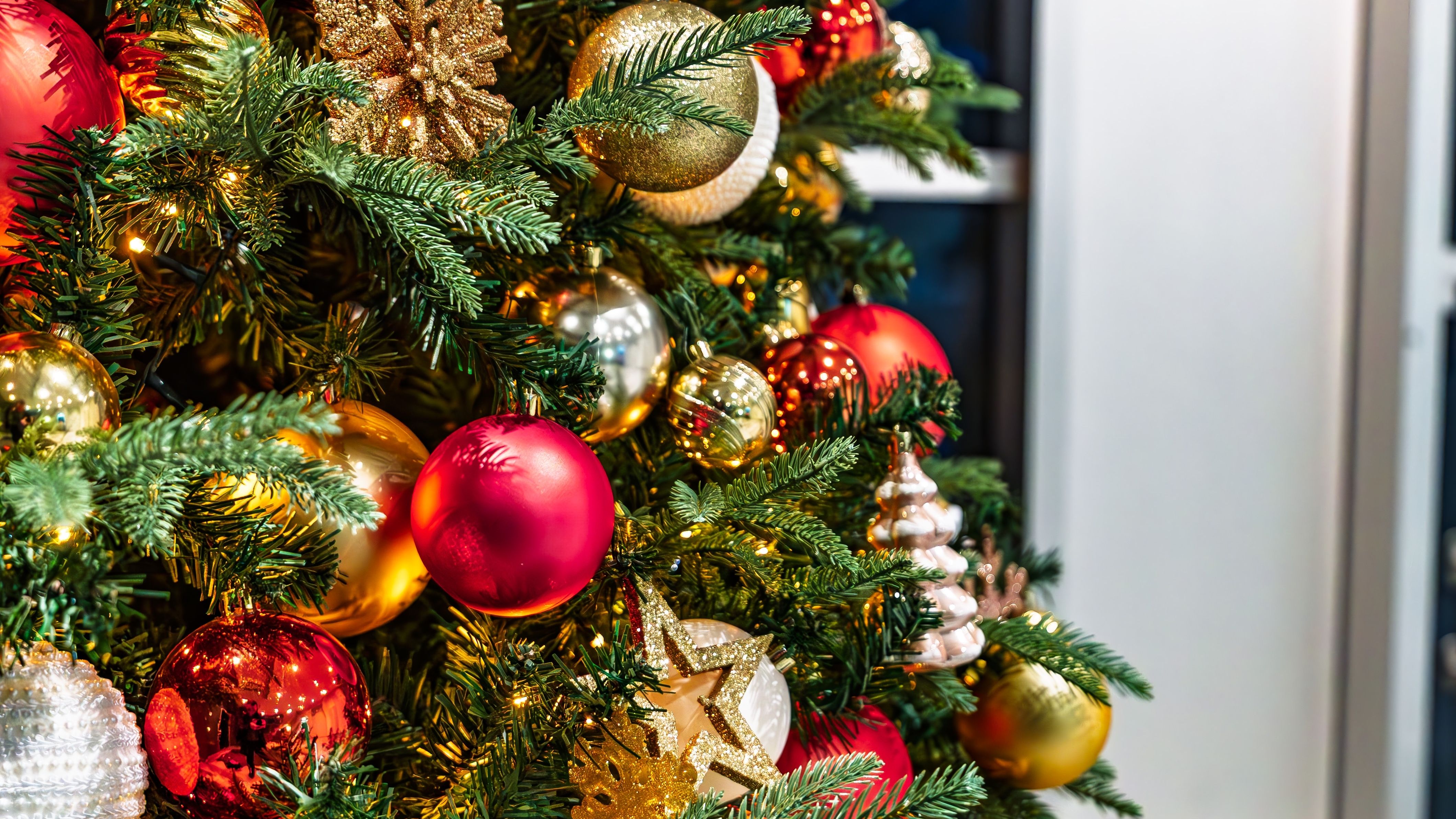 Close-up of a decorated Christmas tree with red and gold baubles, glittery snowflakes and warm fairy lights