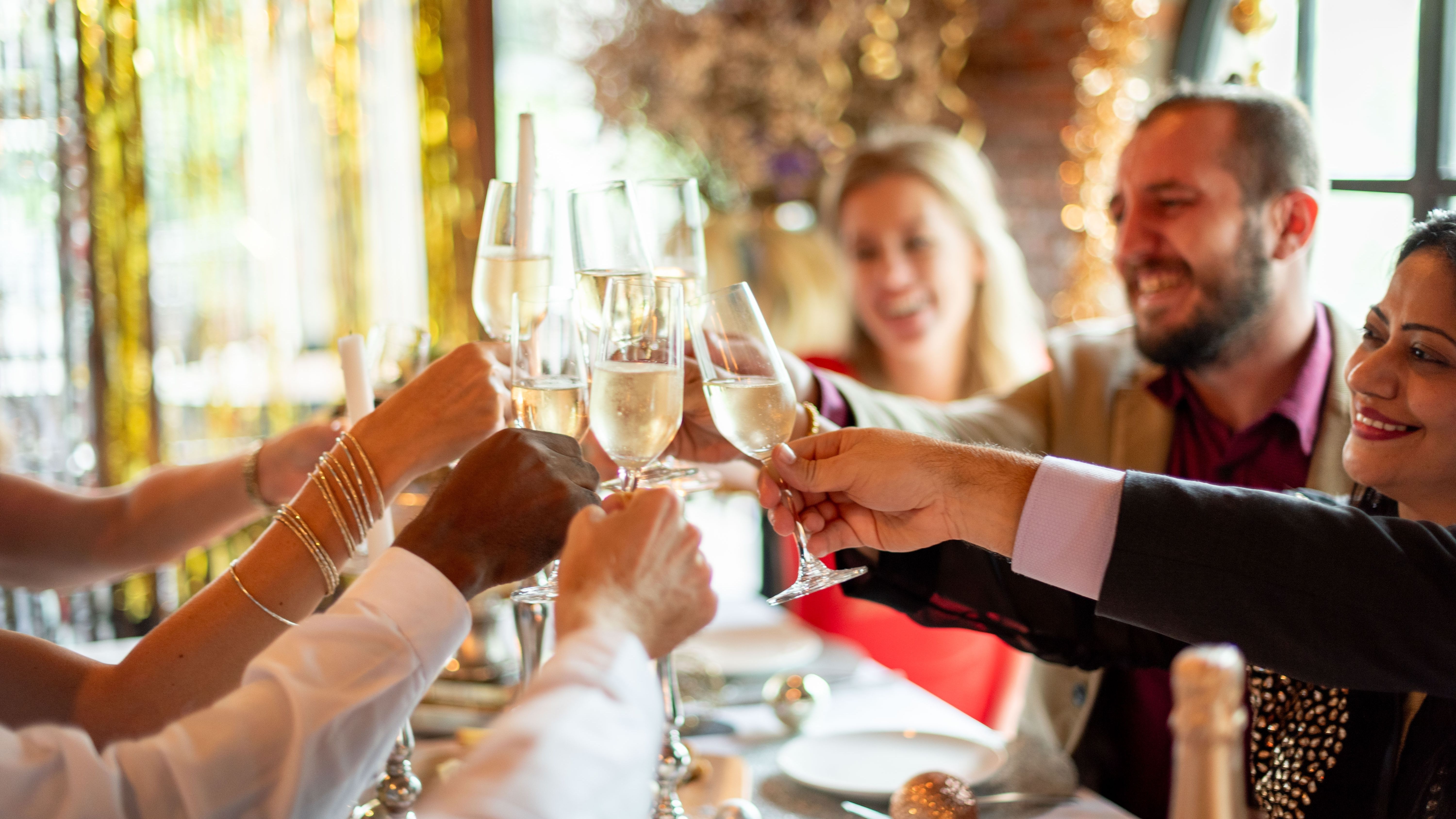Friends clinking champagne flutes in a festive restaurant setting
