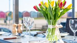 Table set for dining with a vase of red and yellow tulips