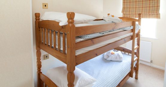 Wooden bunk bed with white pillows and folded towels in a bright bedroom