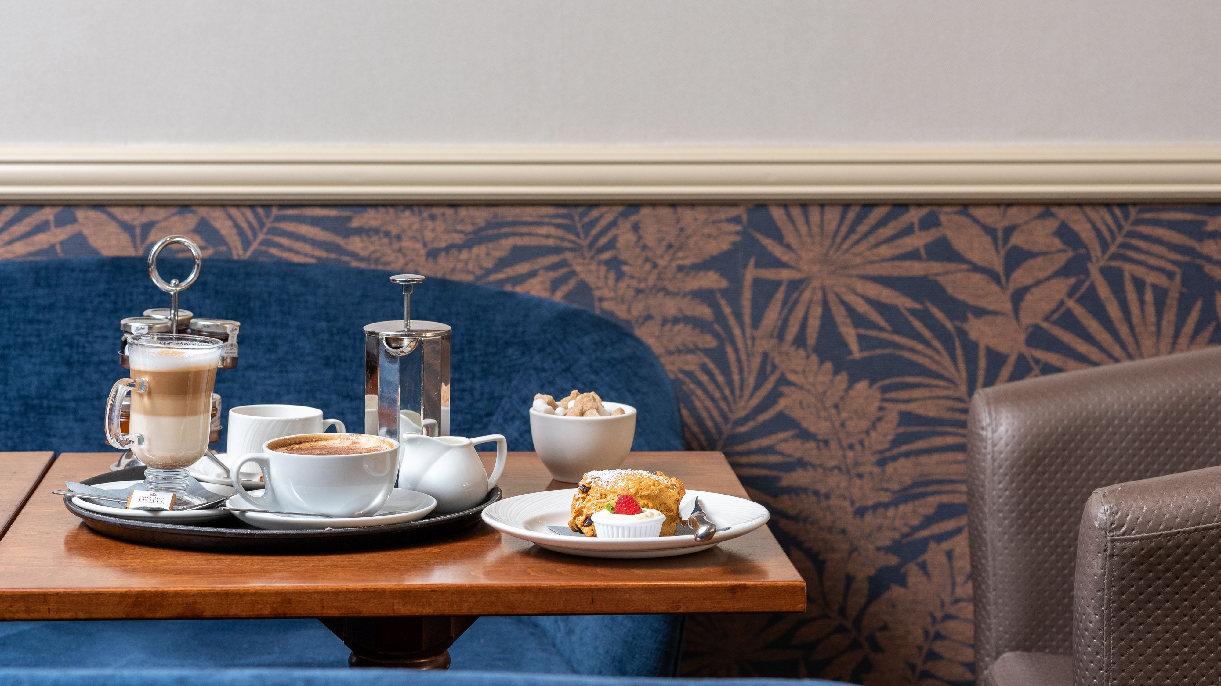 Coffee and pastries served on a wooden table in a hotel lounge booth