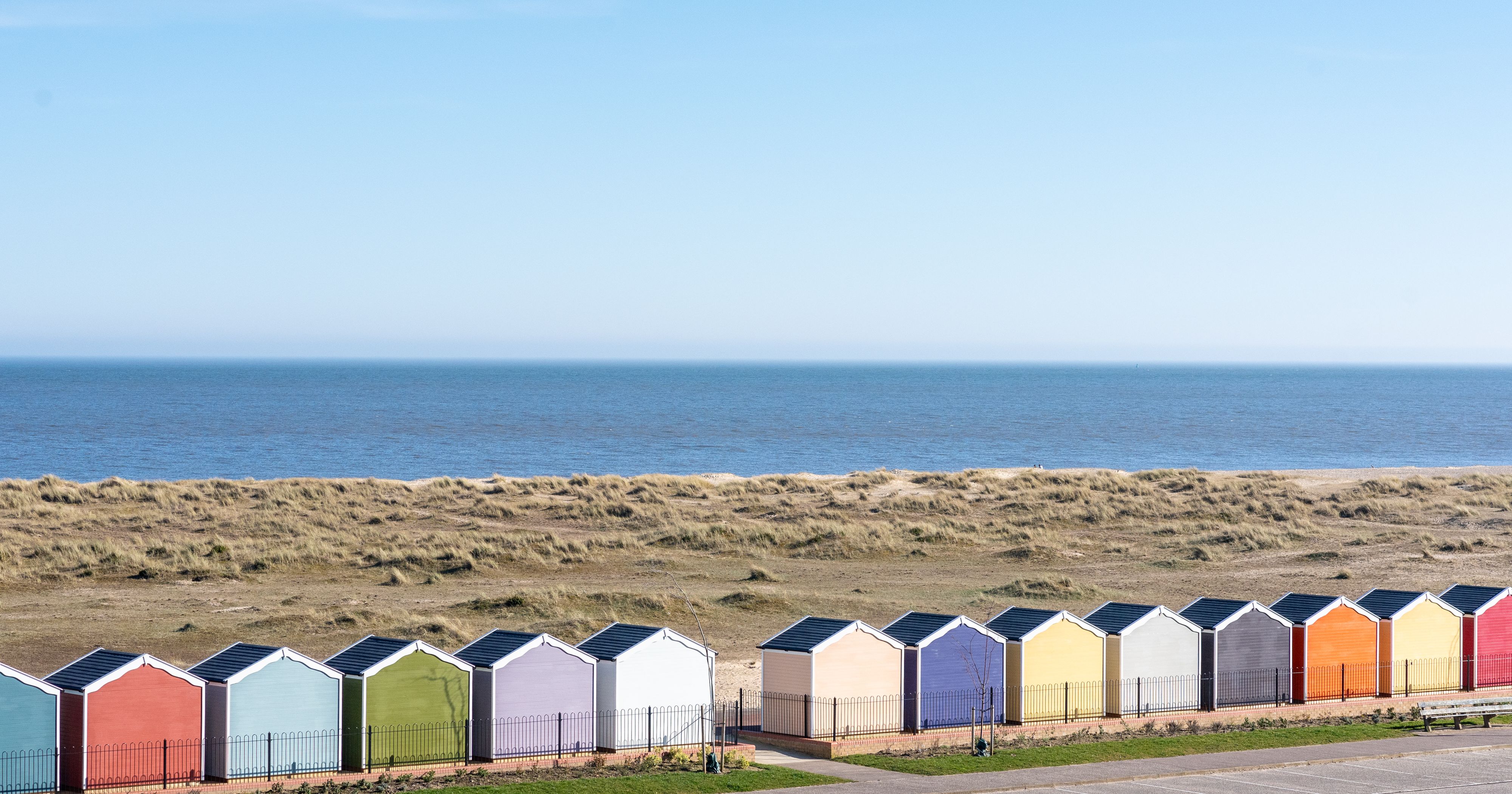 Row of colourful beach huts with the sea and blue sky in the background