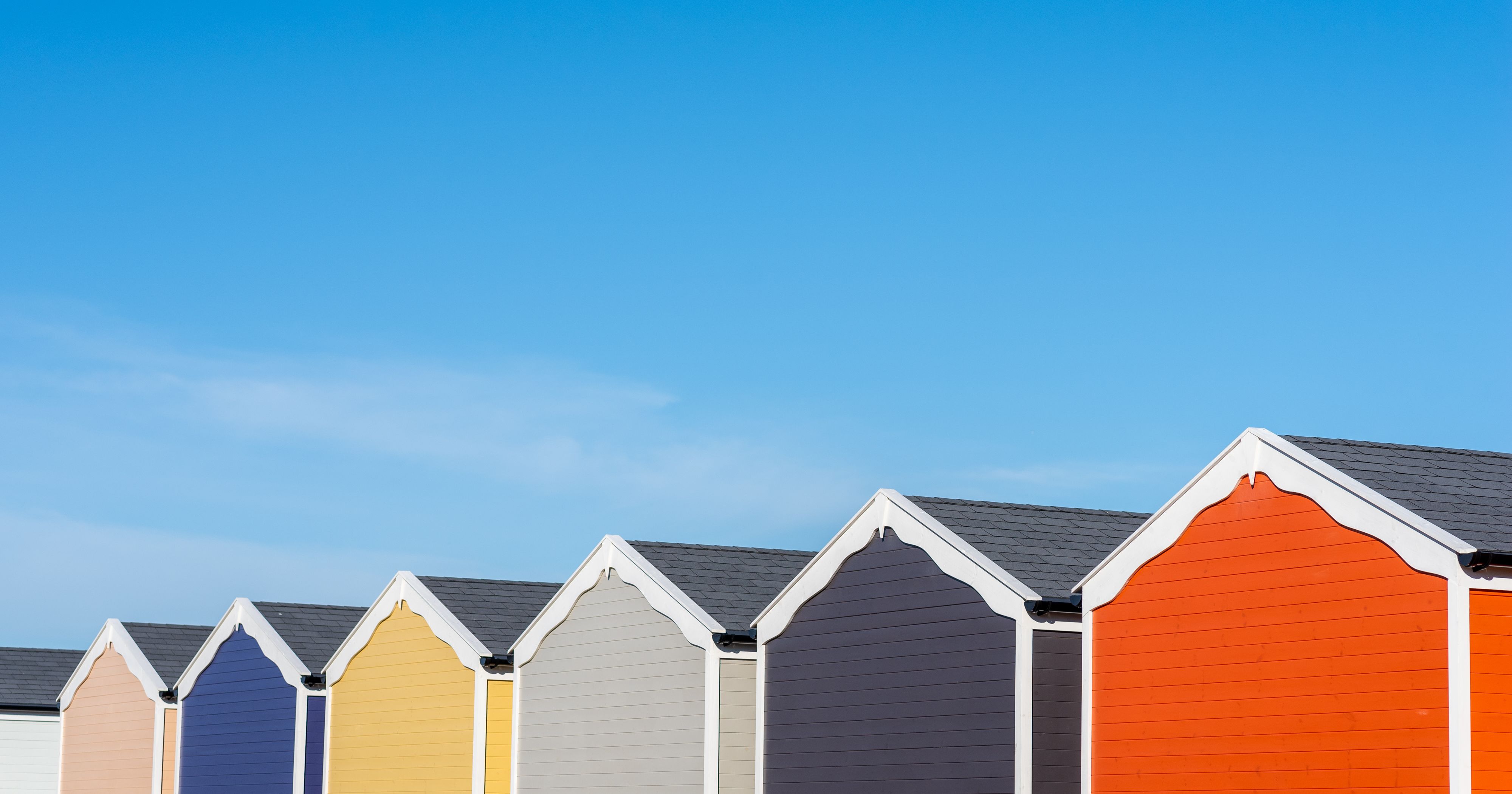 Row of colourful beach huts under a clear blue sky