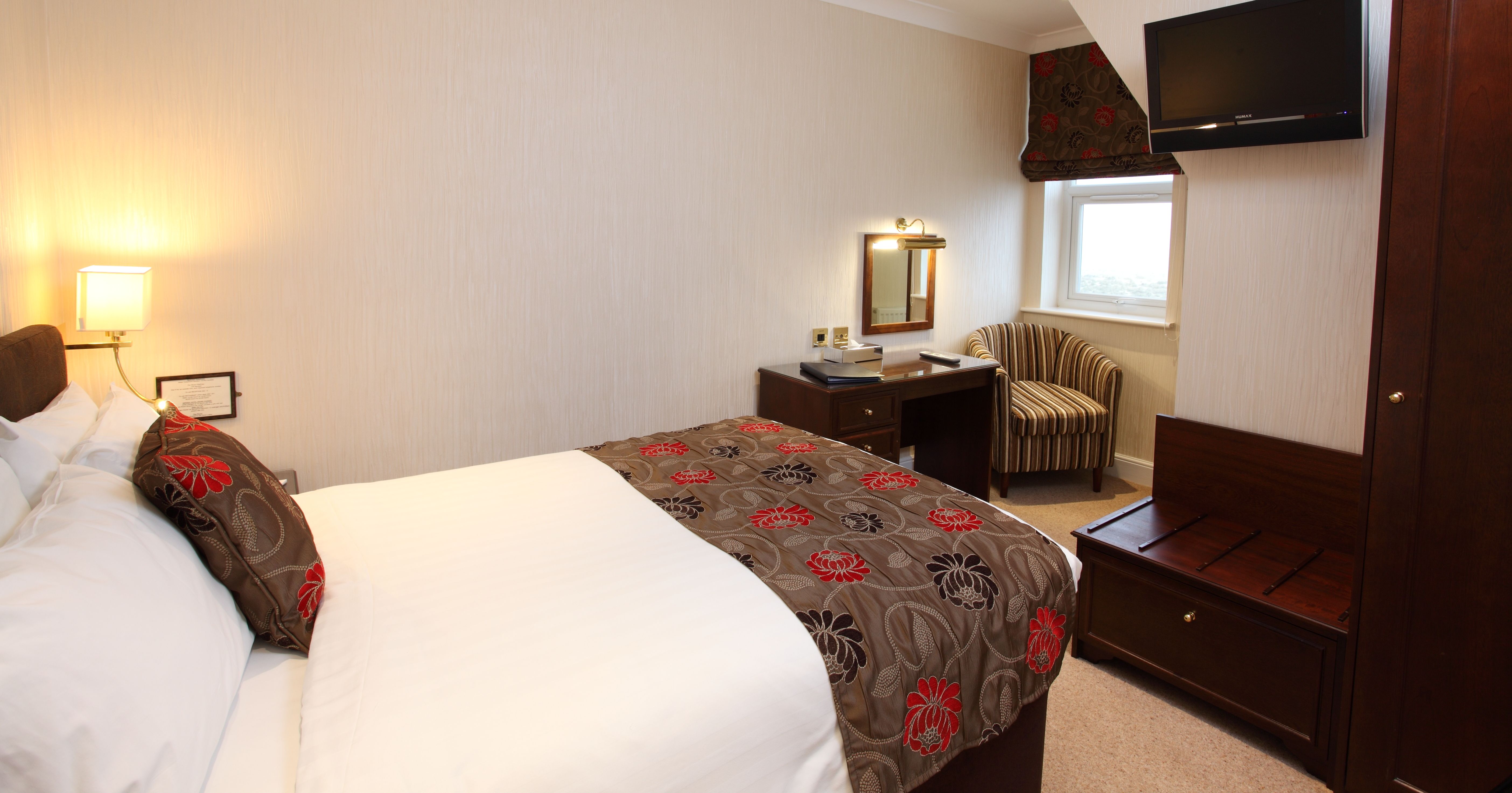 Cosy hotel bedroom with double bed, desk and wall-mounted TV