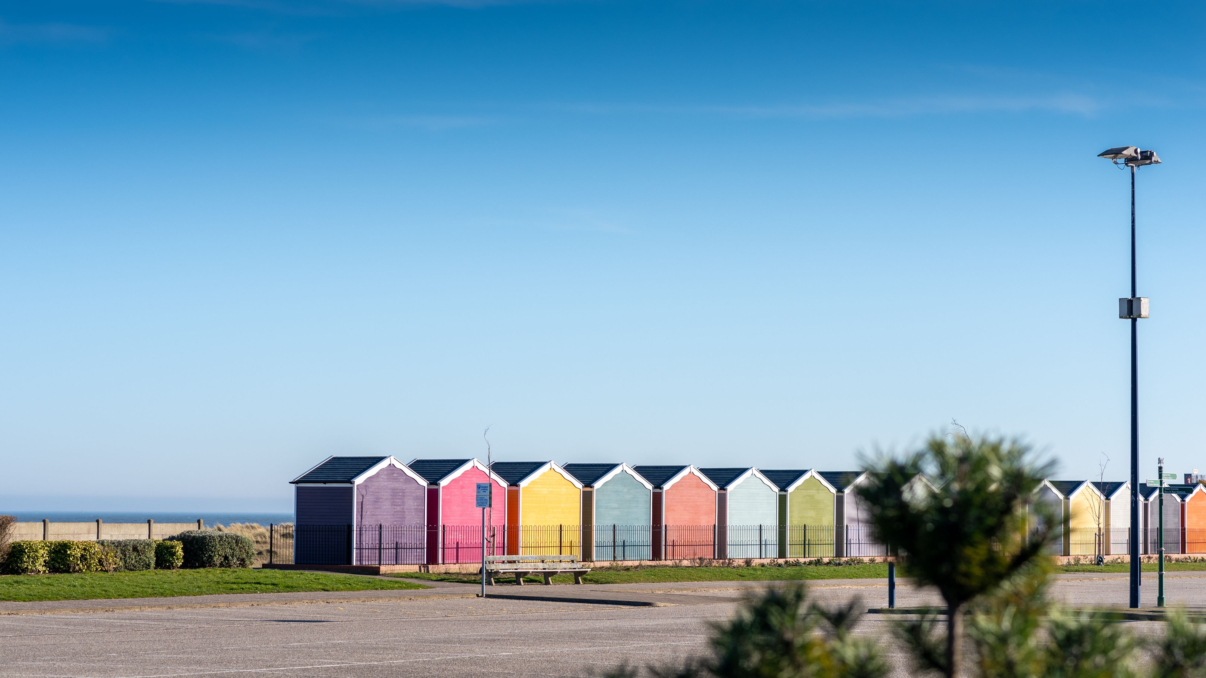 Row of colourful beach huts under a clear blue sky by the seaside