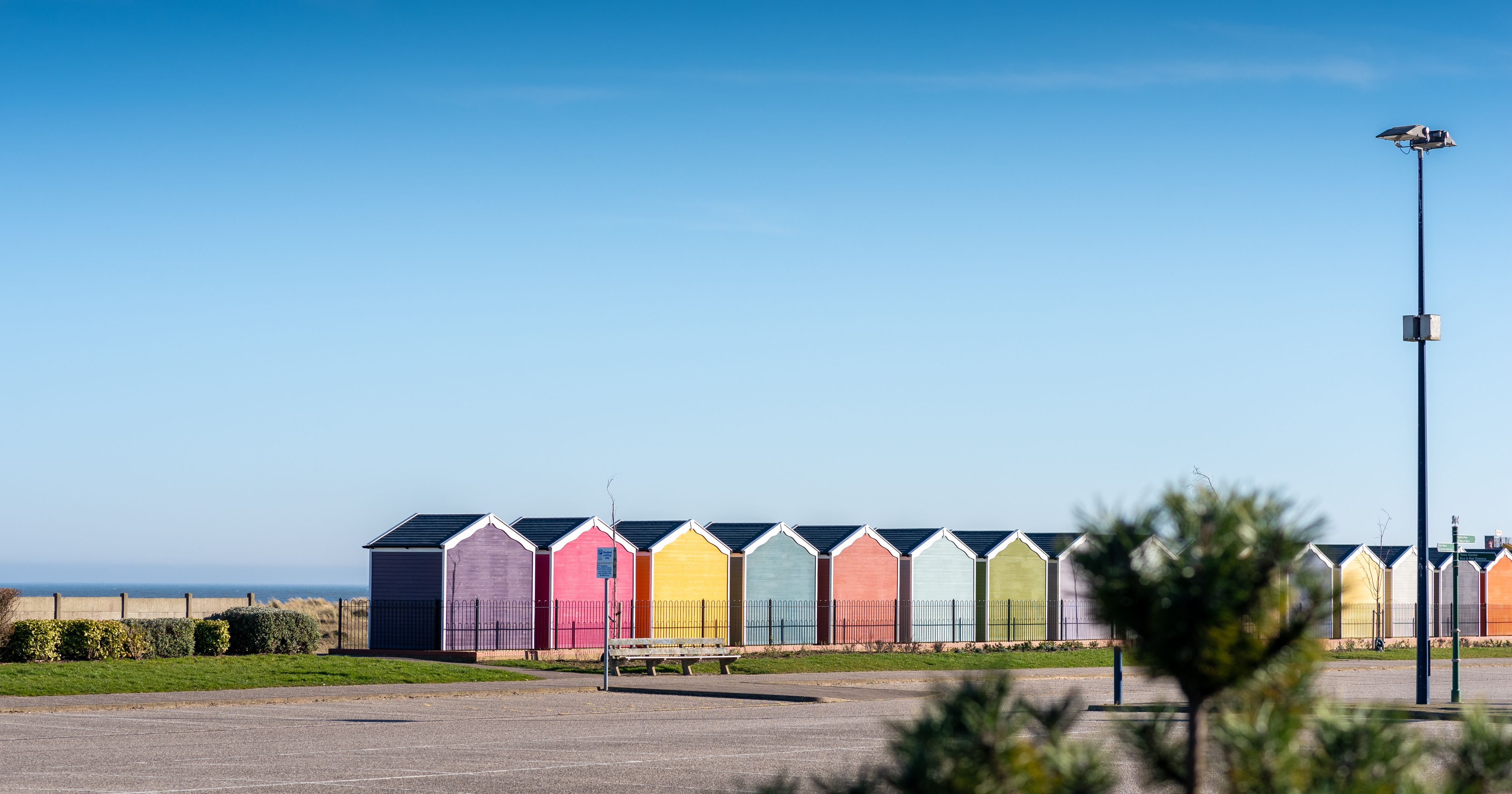 Row of colourful beach huts under a clear blue sky by the seaside