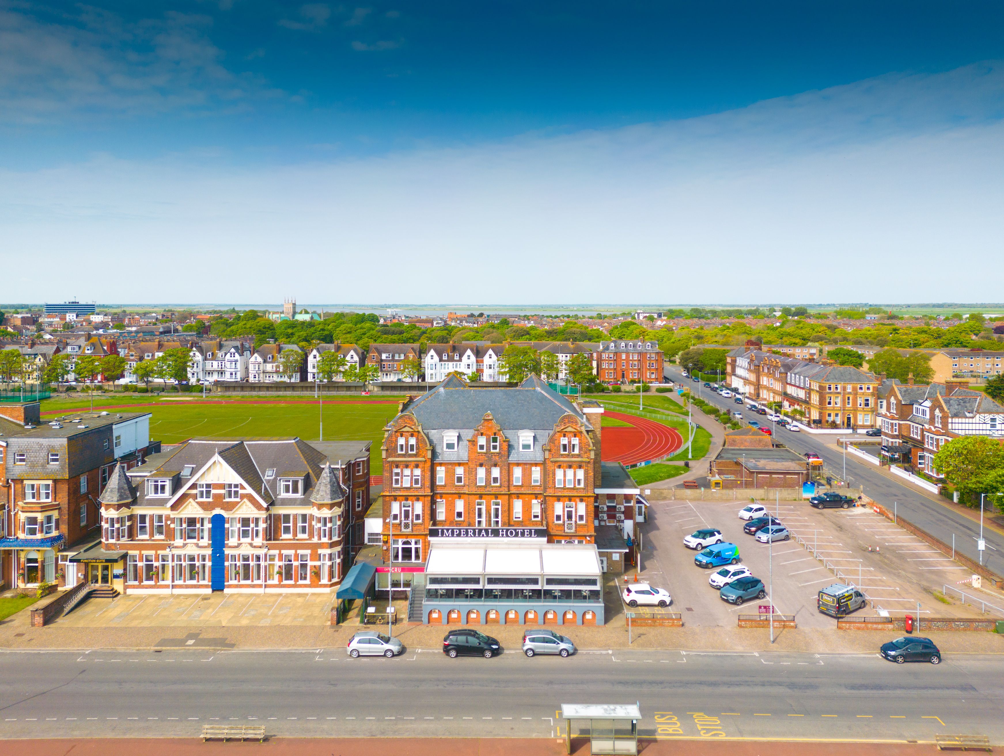 Aerial view of the Imperial Hotel on a seafront road beside a sports field and running track