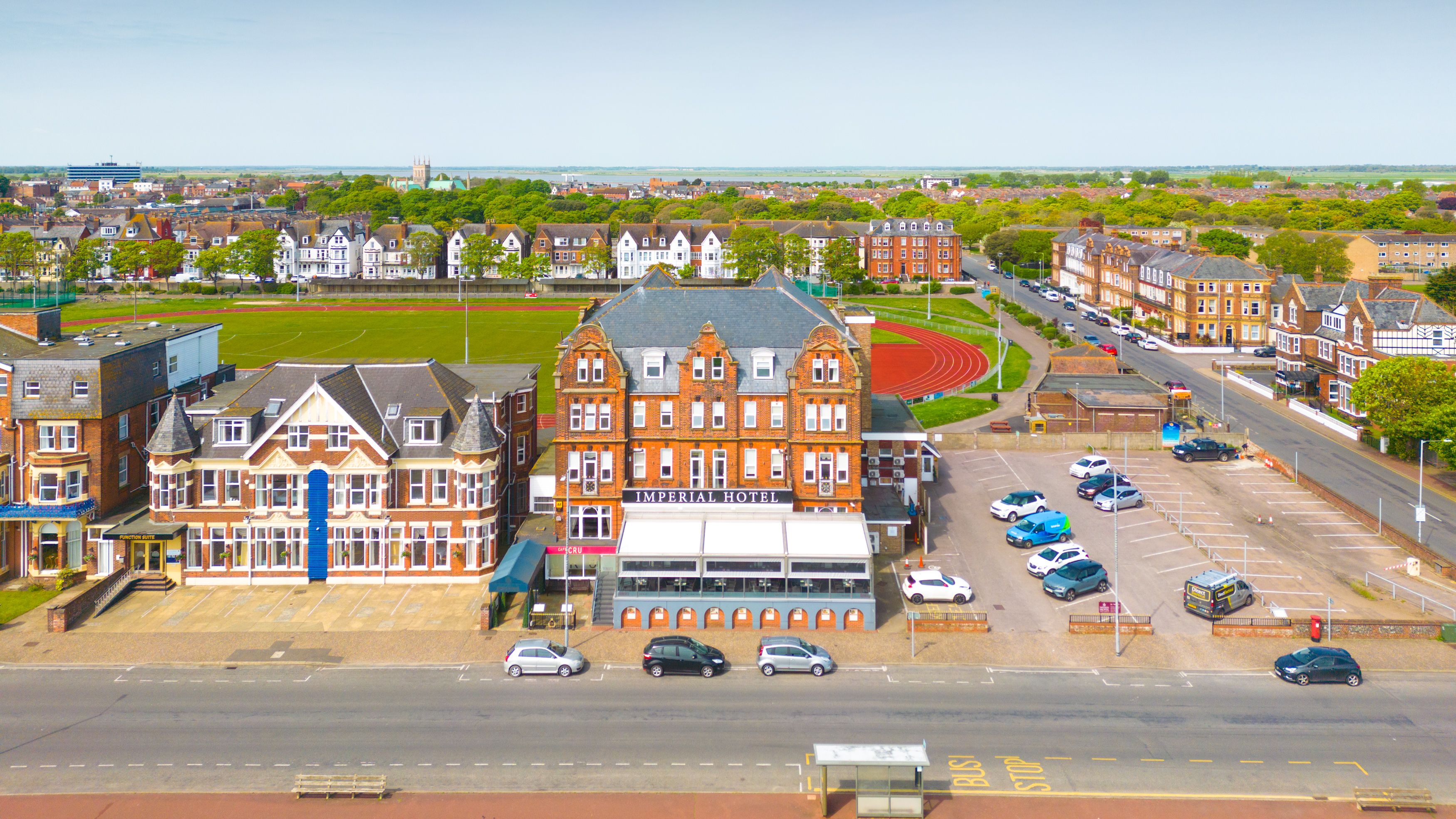Aerial view of the Imperial Hotel on a seafront road beside a sports field and running track