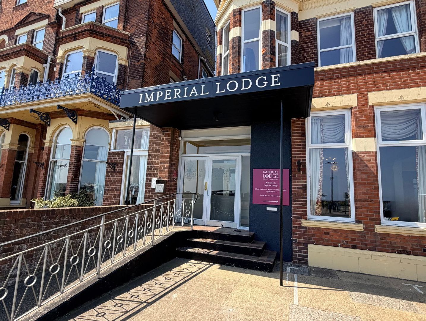Entrance to Imperial Lodge hotel with black canopy sign and brick façade