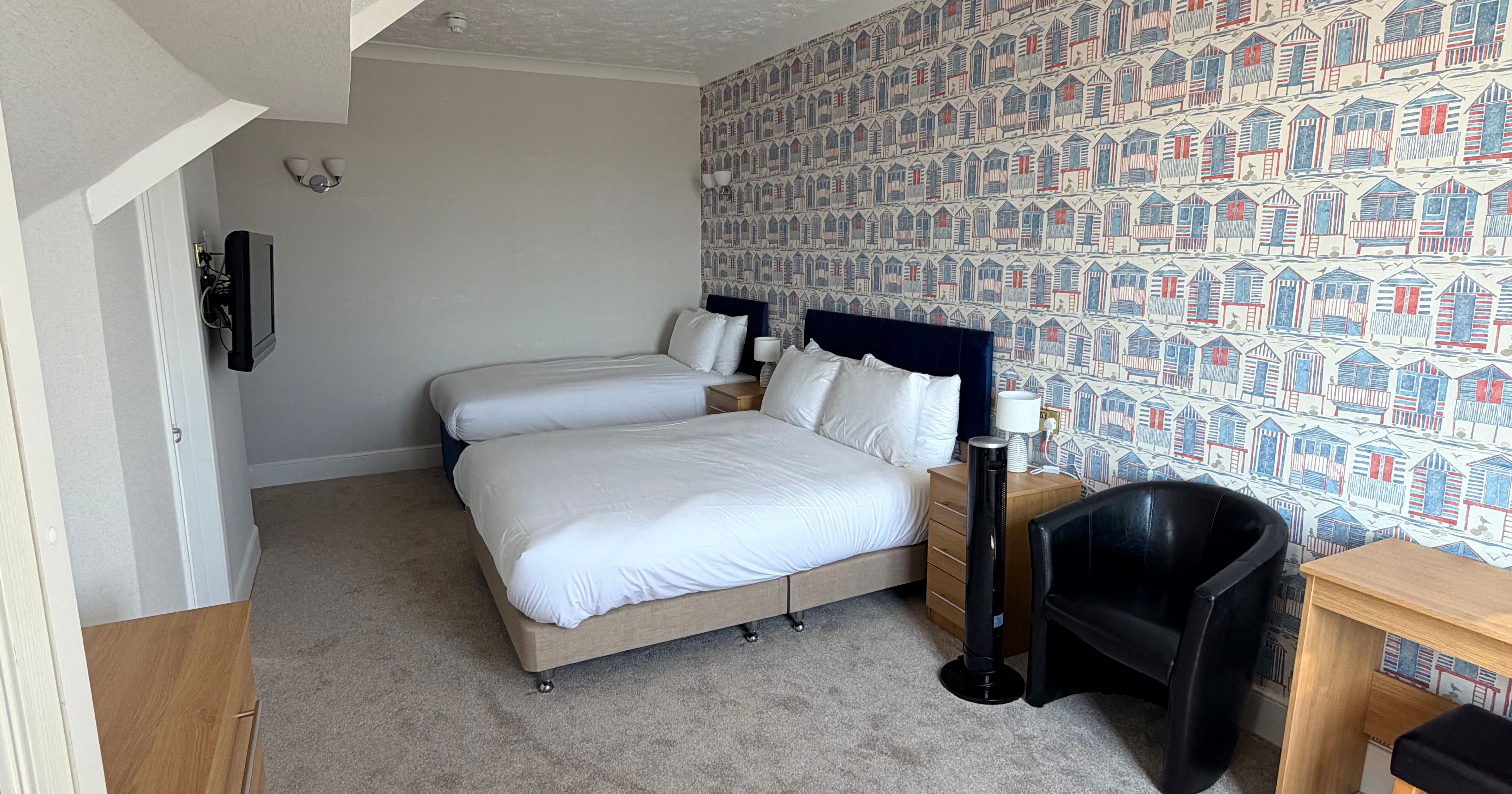 Family lodge bedroom with double bed and single bed, seaside hut wallpaper and desk