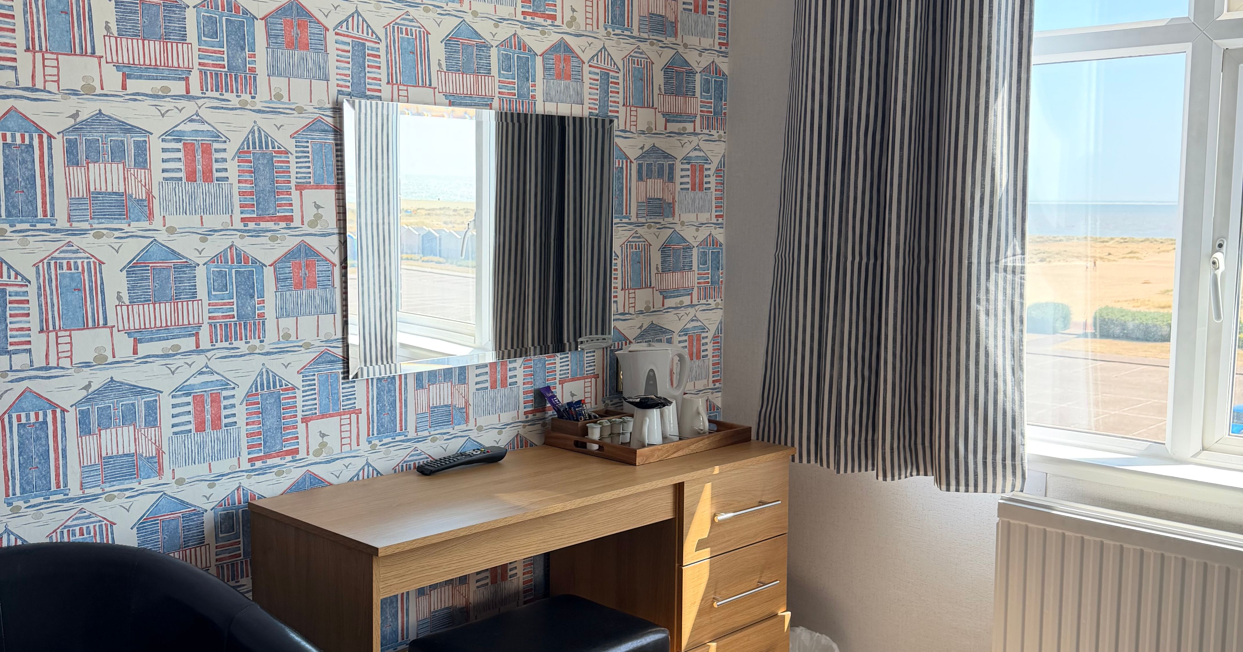 Dressing table with mirror by a window overlooking the sea in a family lodge bedroom