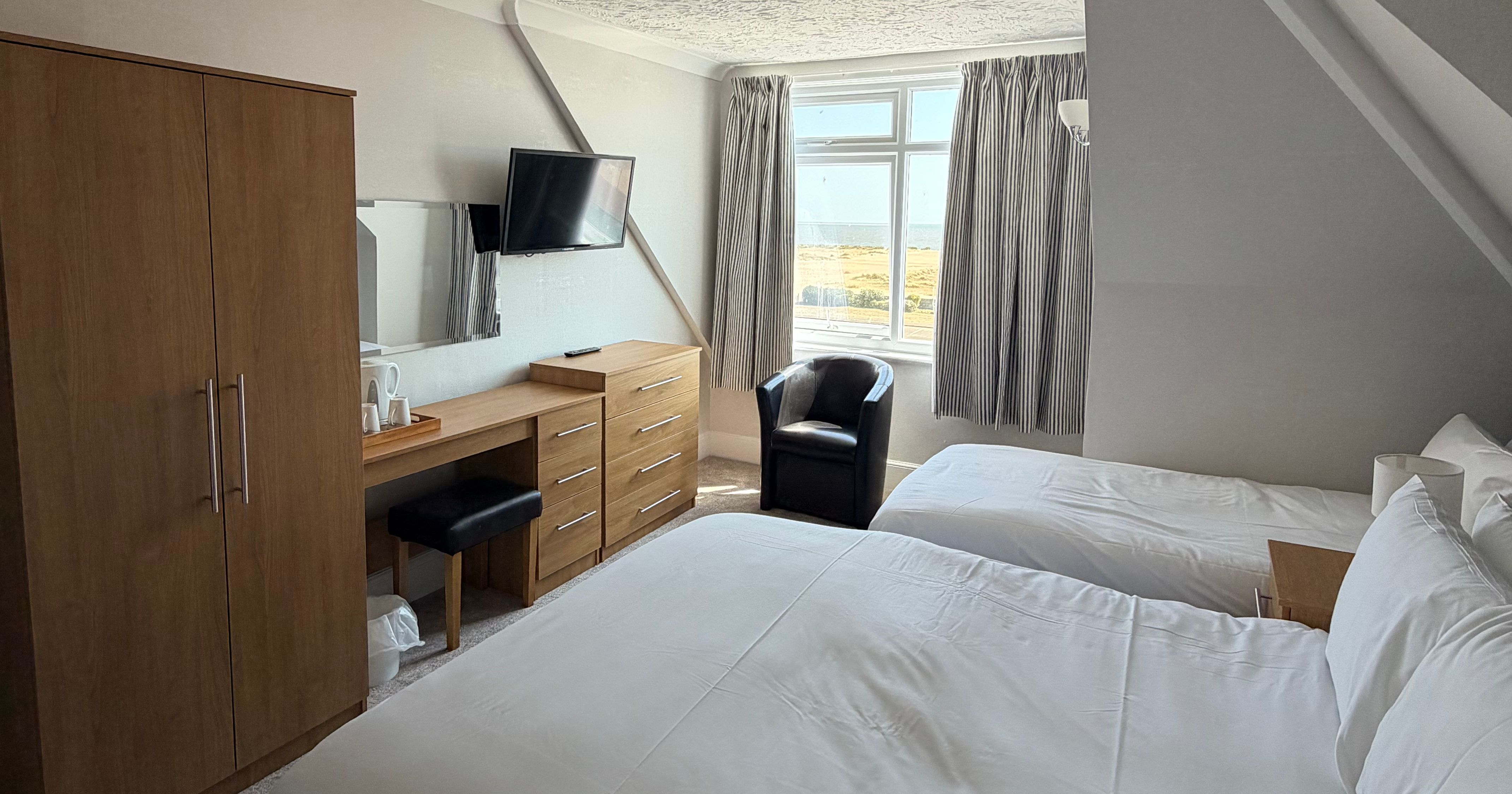 Twin bedroom with sea-view window, desk, wardrobe and chair