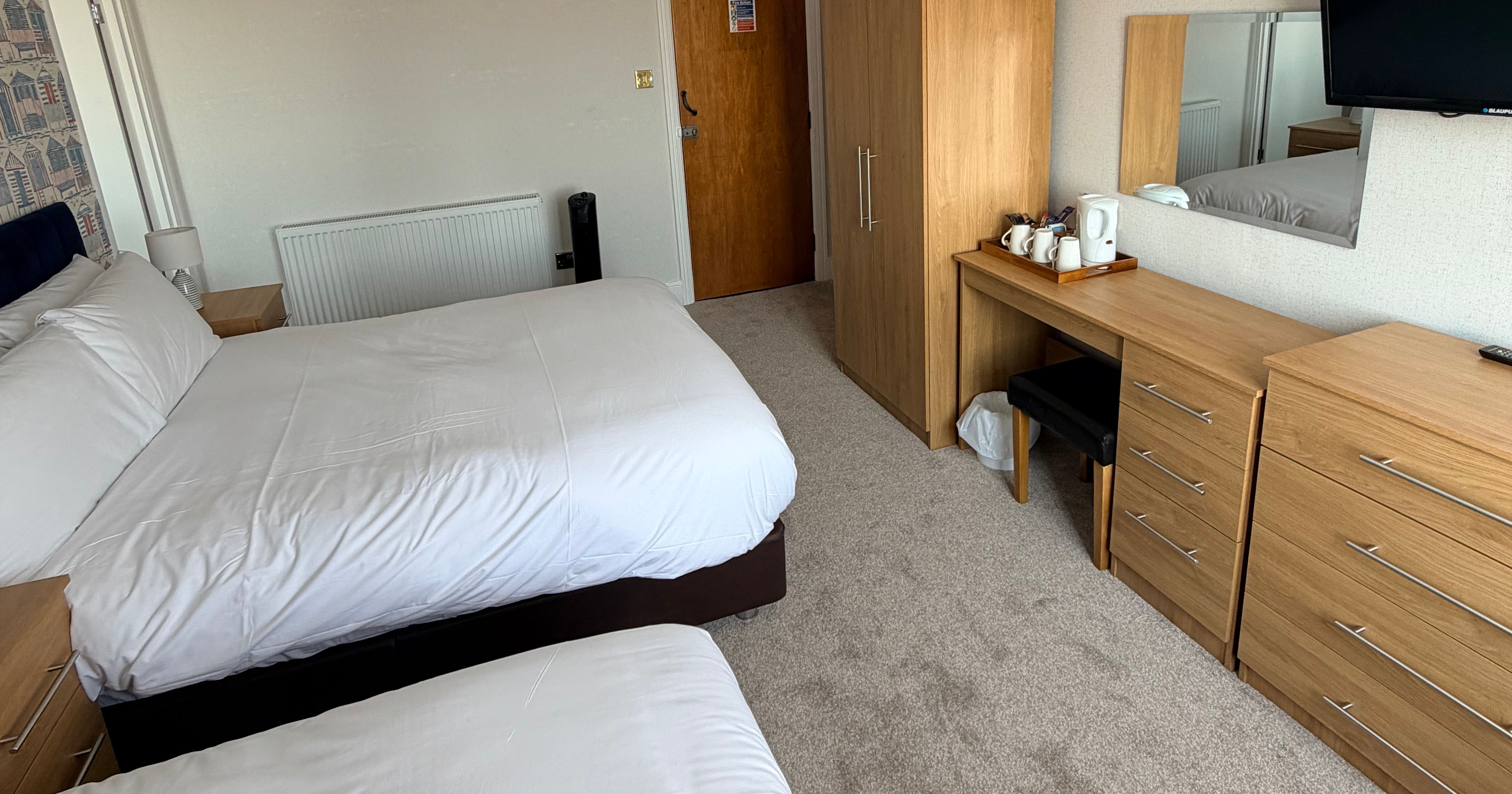 Family lodge bedroom with two single beds, wooden wardrobe and dressing table with wall-mounted TV