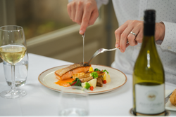 Man cutting into a plate of fish and vegetables