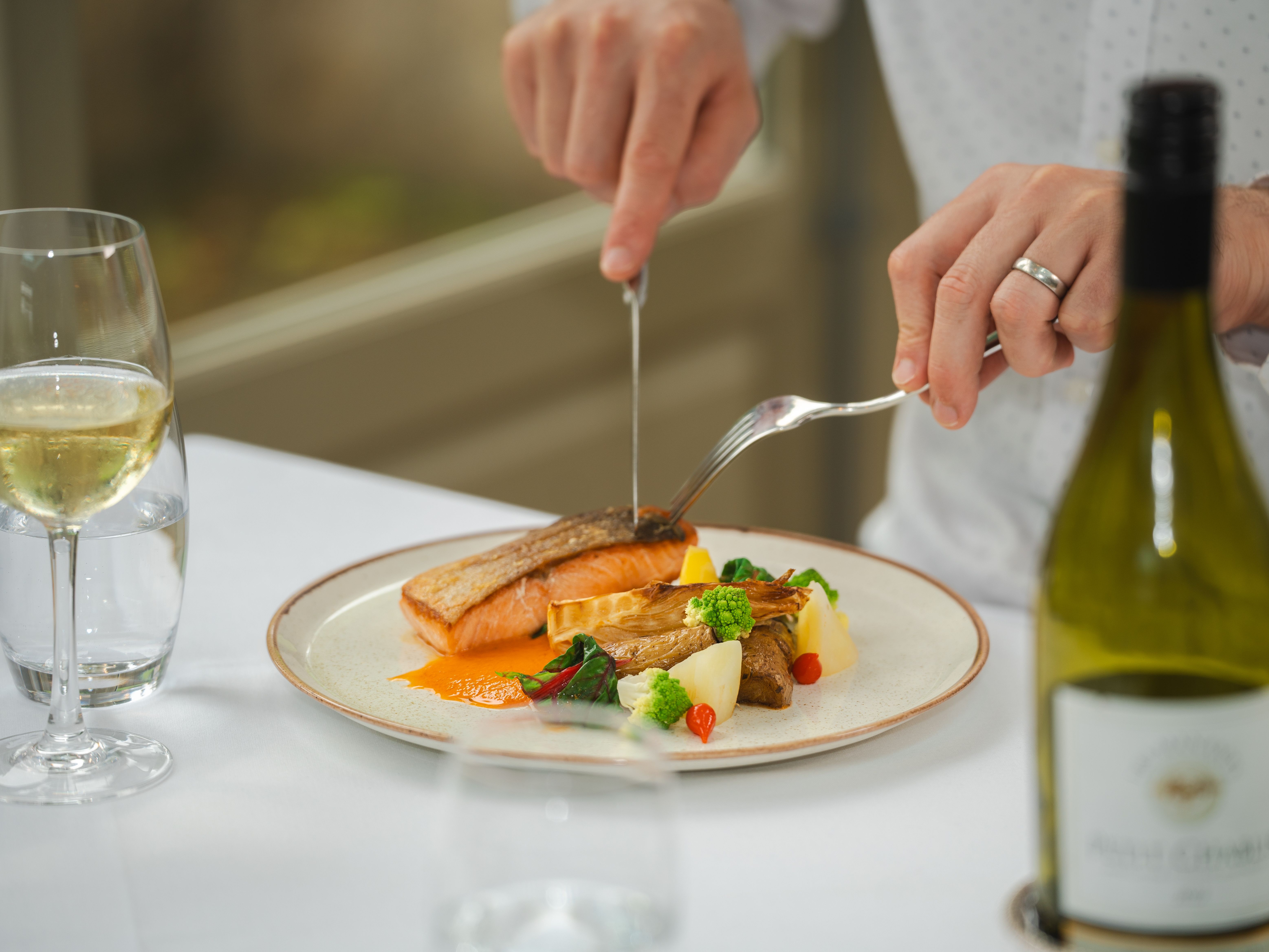 Man cutting into a plate of fish and vegetables