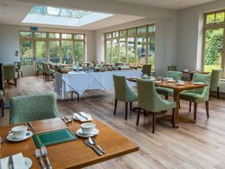 Room with lots of windows and a few tables inside laid out for dinner