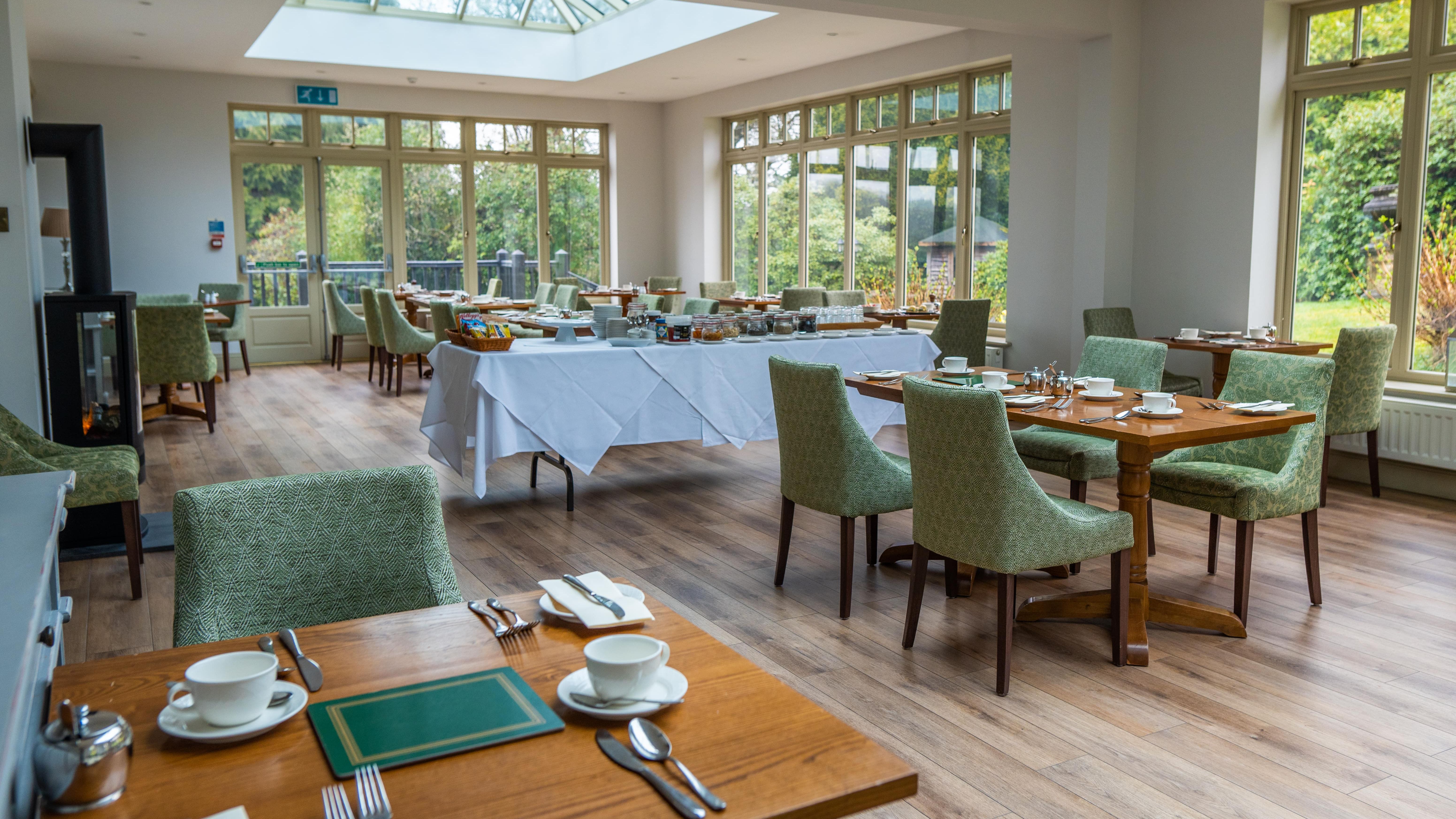 Room with lots of windows and a few tables inside laid out for dinner