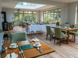Room with lots of windows and a few tables inside laid out for dinner