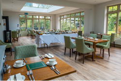 Room with lots of windows and a few tables inside laid out for dinner