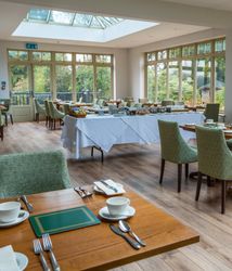 Room with lots of windows and a few tables inside laid out for dinner