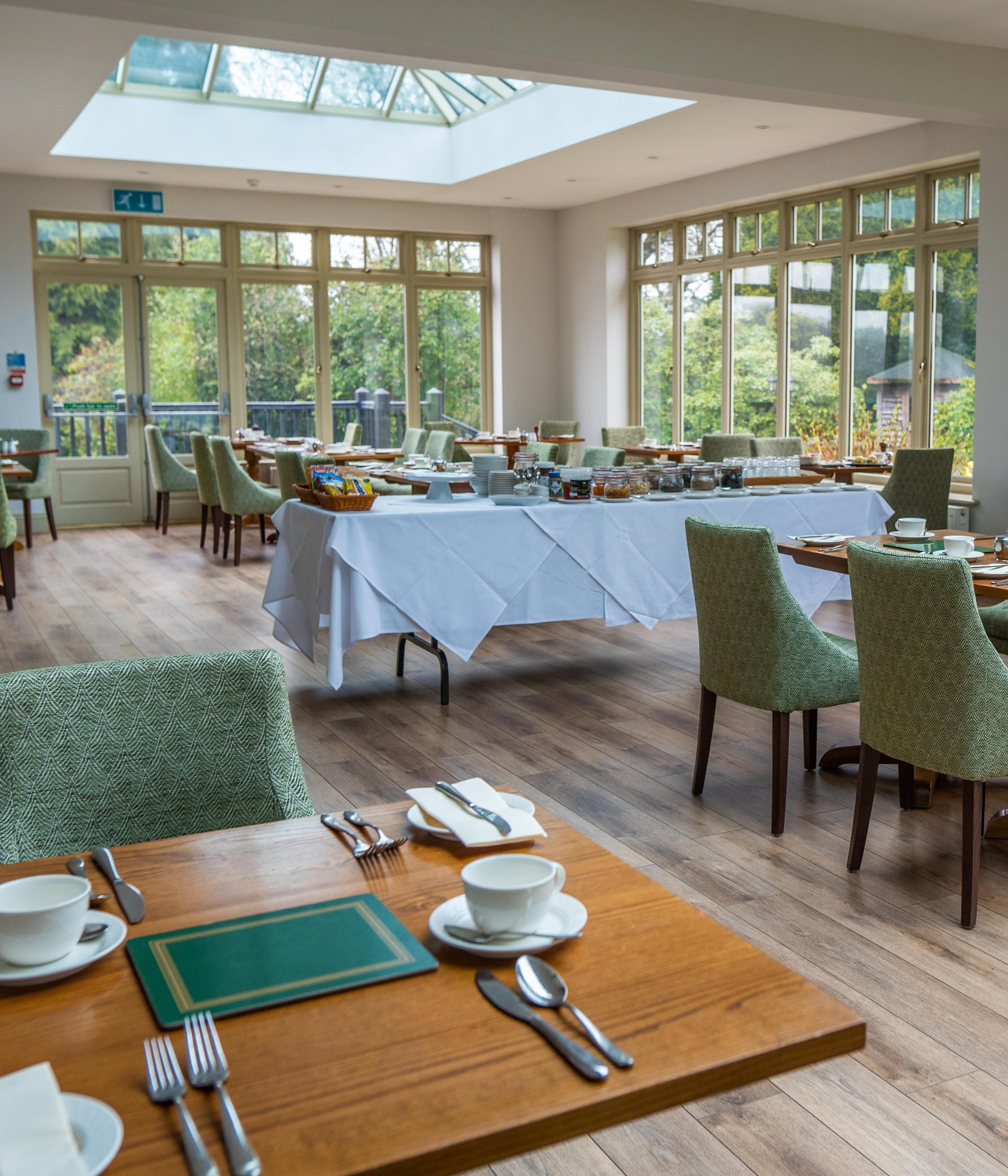 Room with lots of windows and a few tables inside laid out for dinner