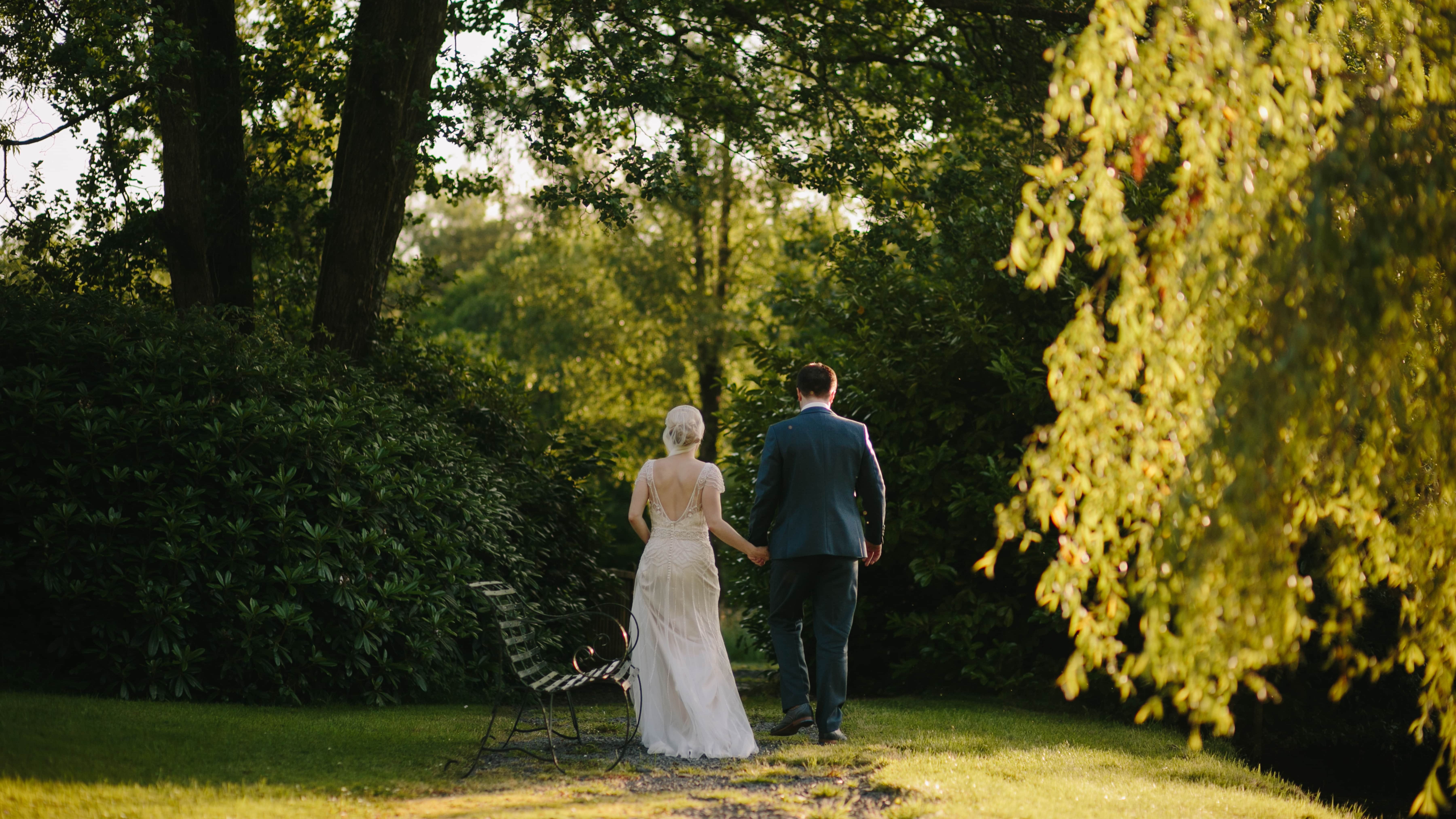 Bride and groom walking through grass path